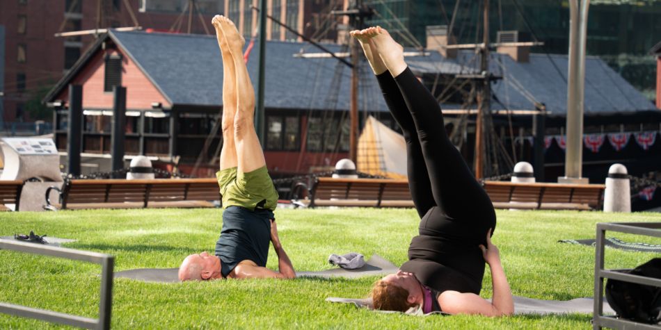 Two guests at waterfront yoga doing a Legs Up yoga pose.