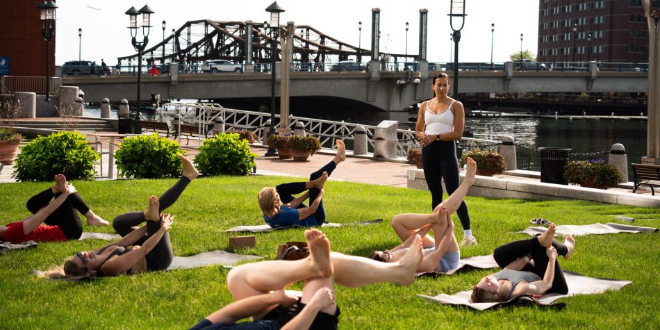 Guests in a reclined pigeon pose as instructor looks on.