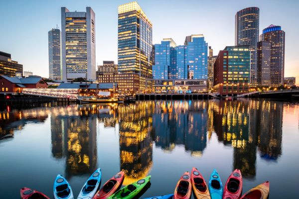 Kayaks in the harbor facing the waterfront buildings during sunset.