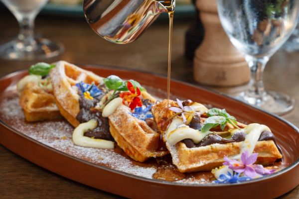 syrup being poured over waffles