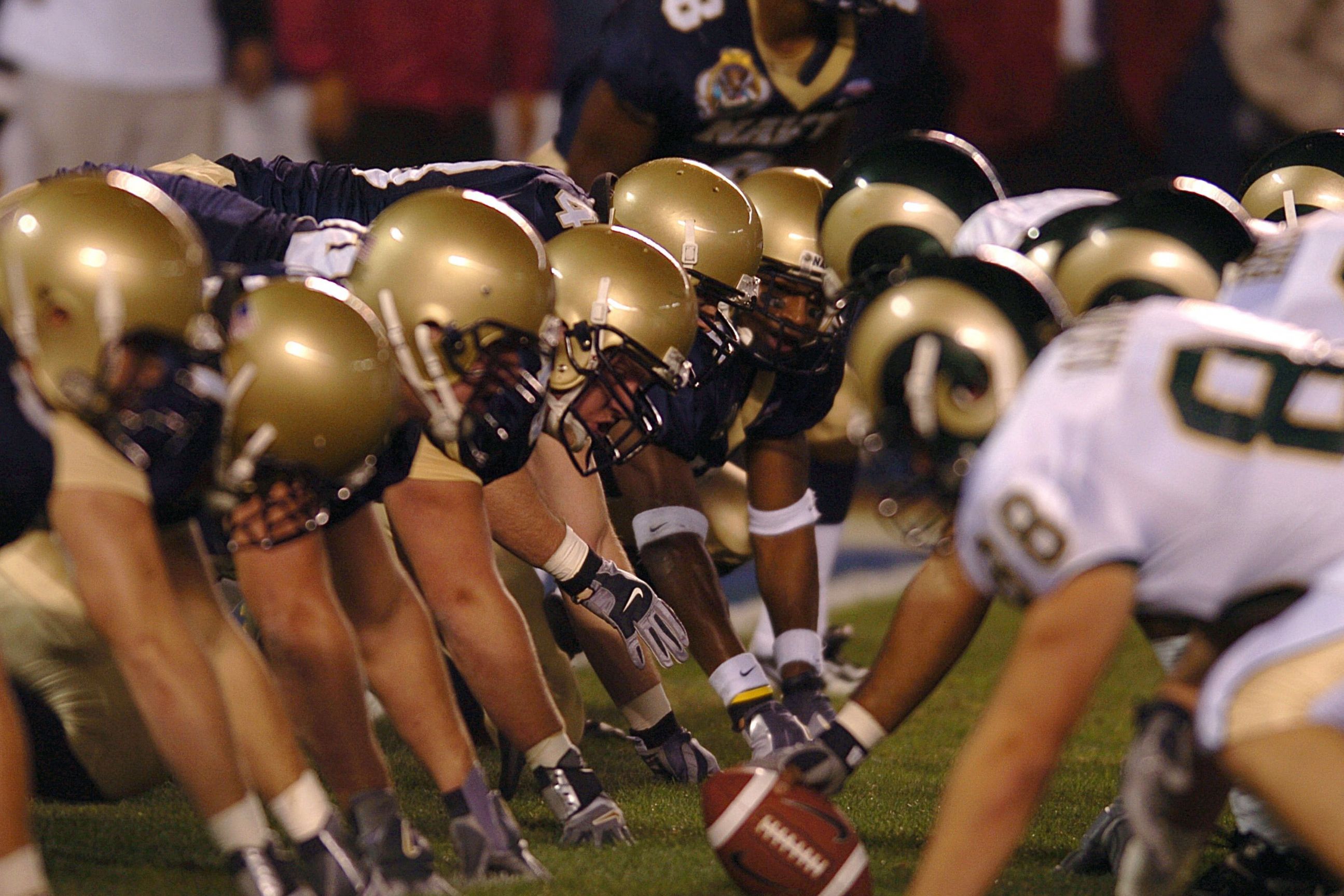College football teams line up at the line of scrimmage during a game under stadium lights in Boston.