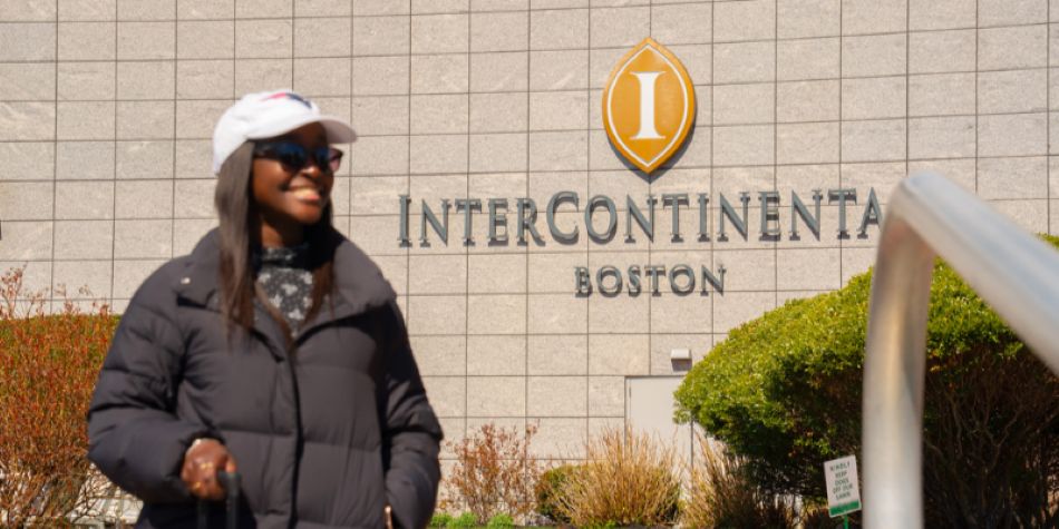 Woman standing outside InterContinental Boston in front of the hotel sign.