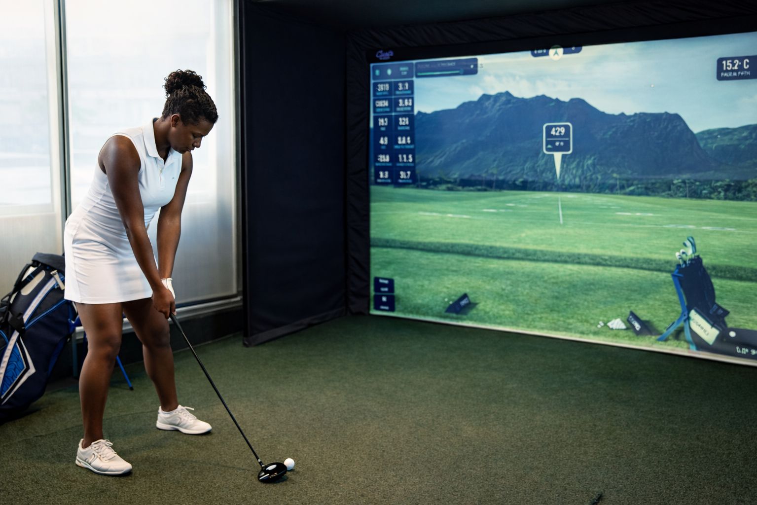 Woman about to take a swing on the golf simulator.