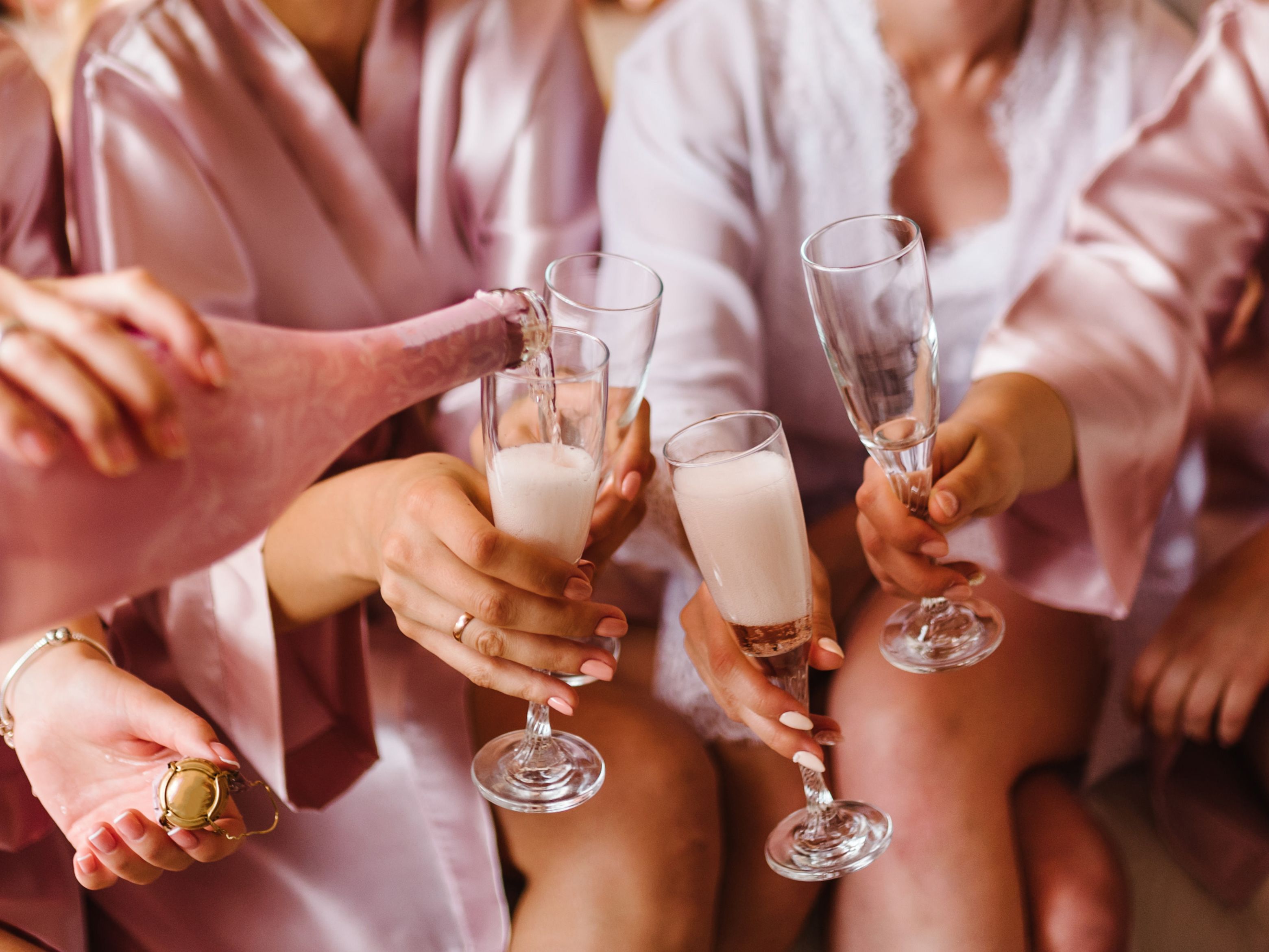 Bridal party in pink robes toasting with champagne.
