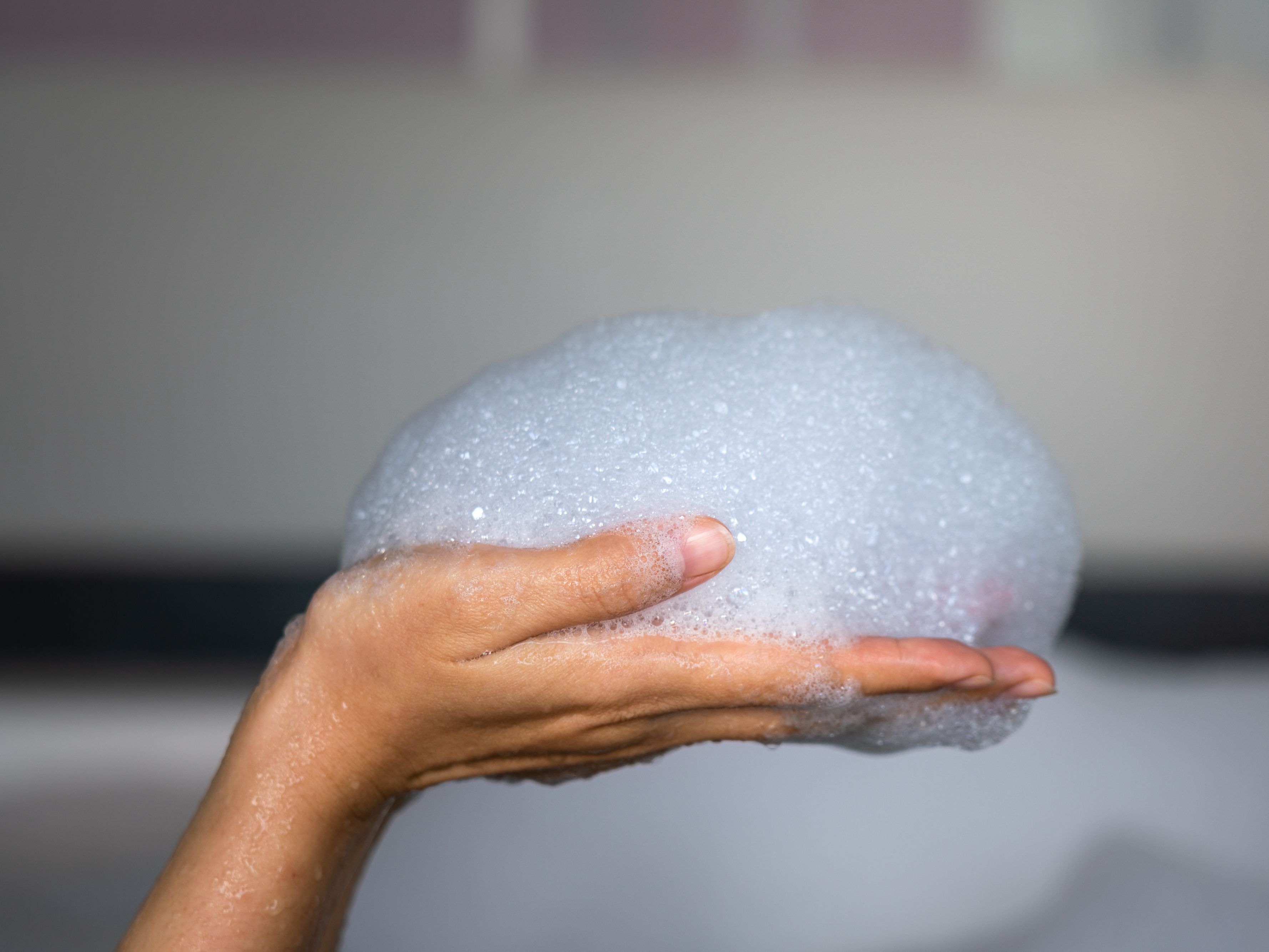 Hand in the bathtub full of soap bubbles.