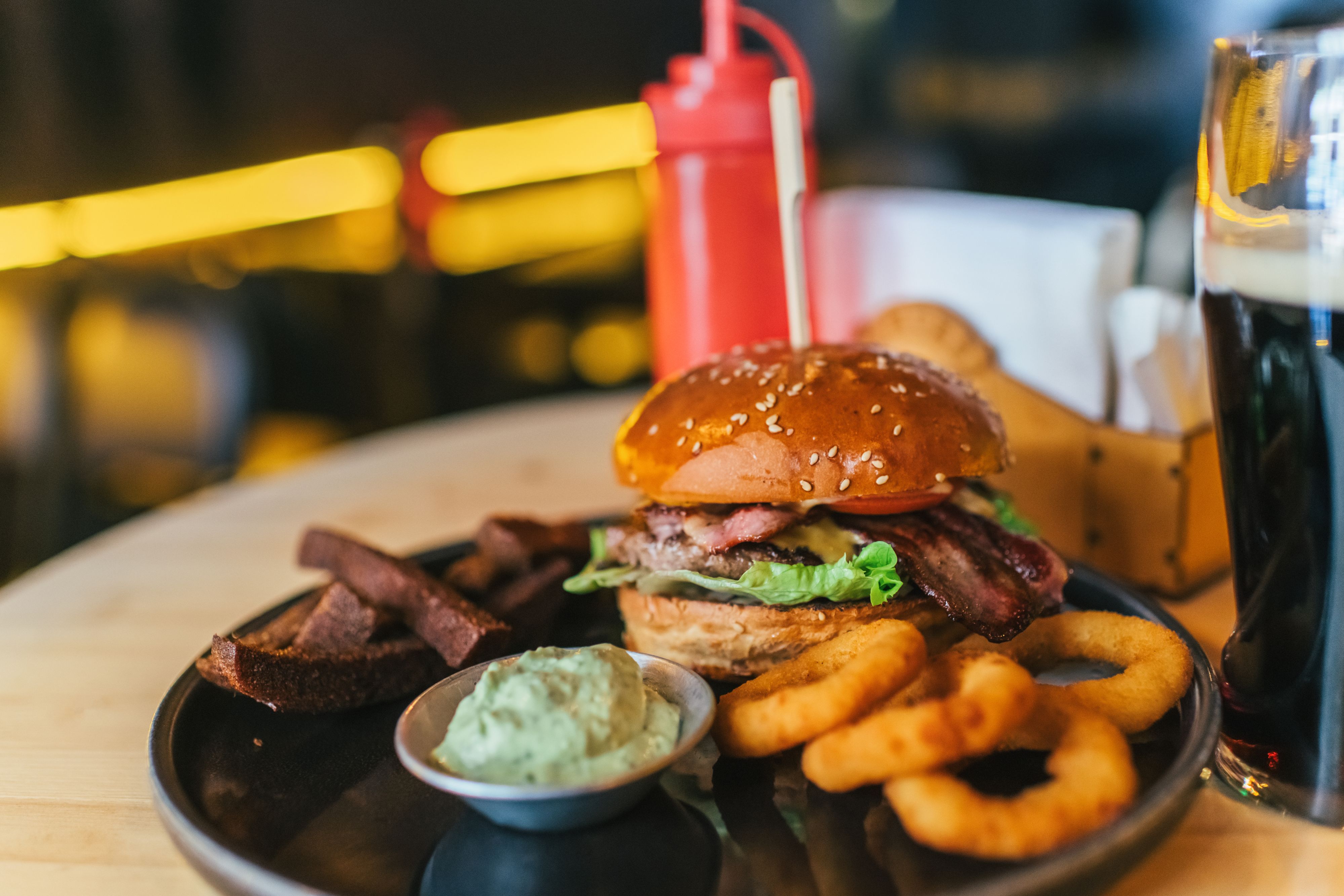 A stacked burger with onion rings and fries.