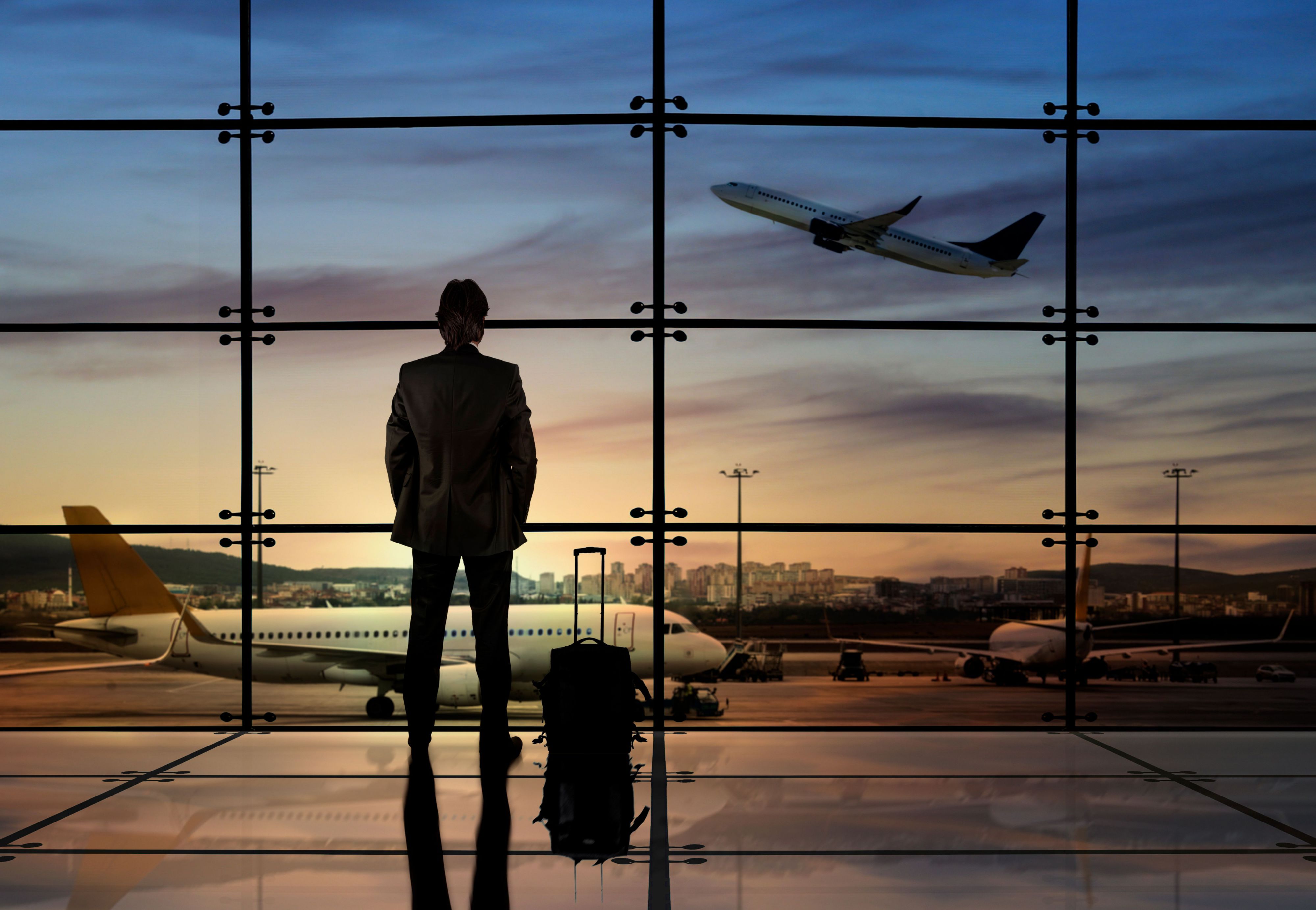 business man at airport watching airplanes take off during sunset