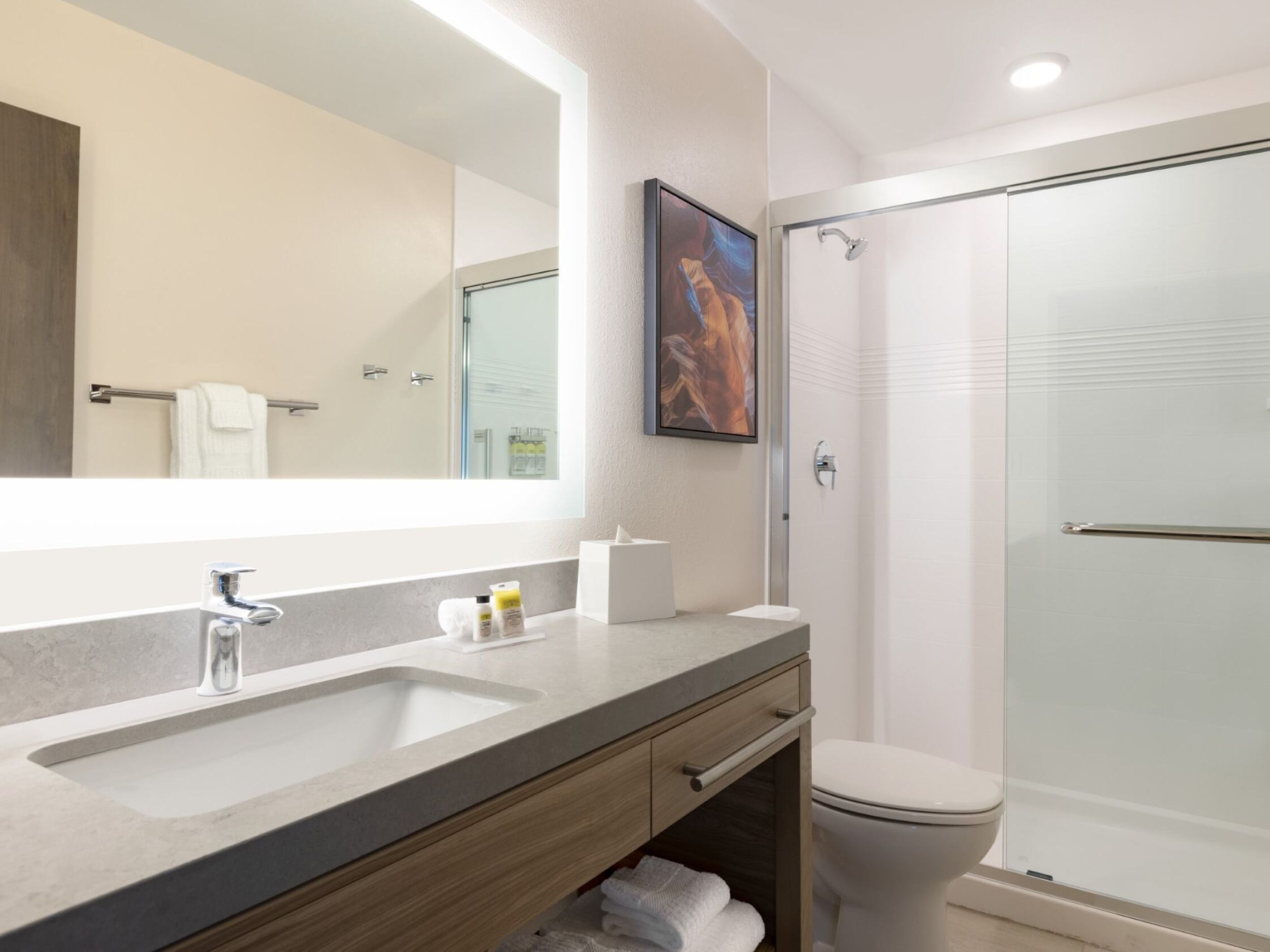 A bright bathroom with a sliding glass door shower, toilet, and sink 