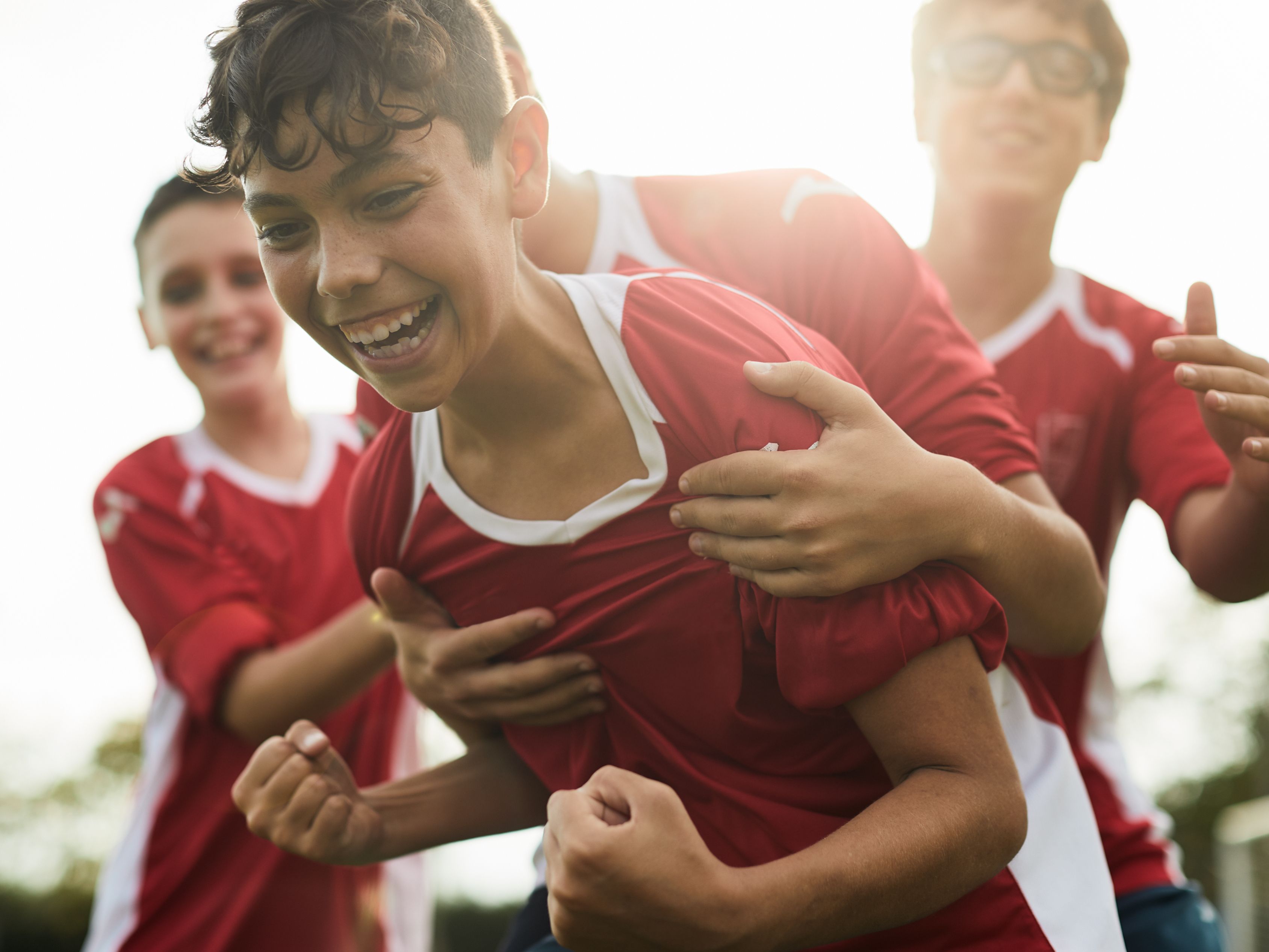 Boys rough housing in sports uniforms