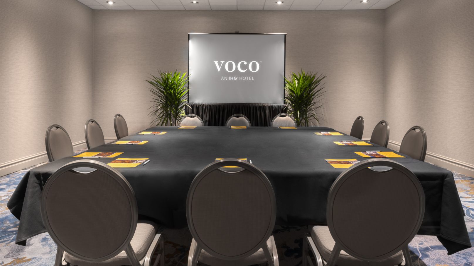 Large square table with projector screen in conference room