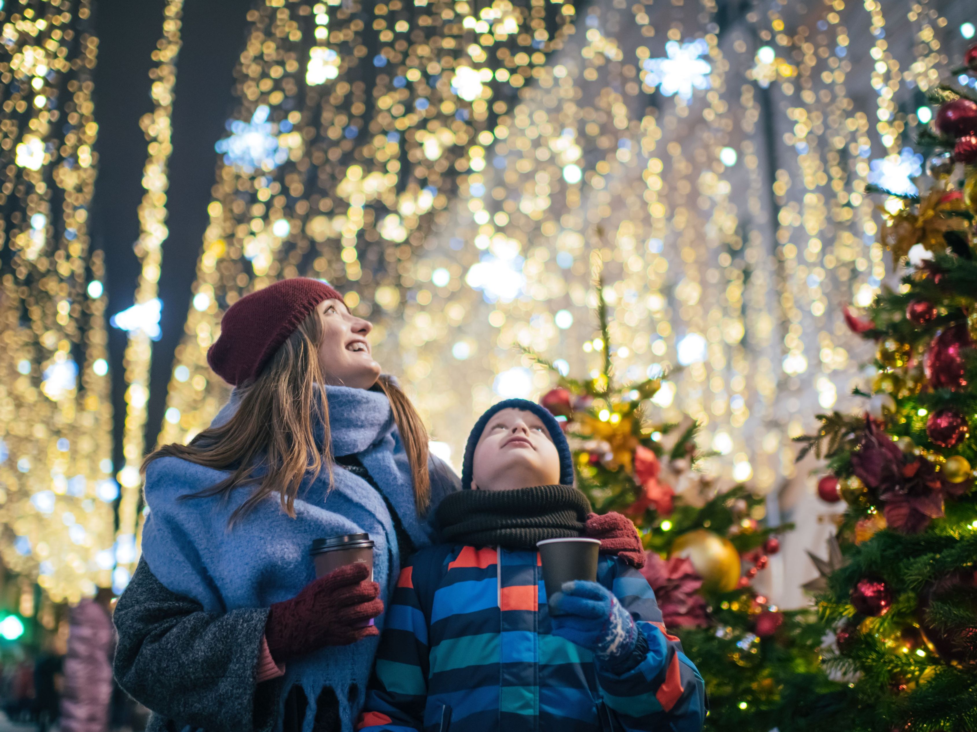 Mom and son drinking hot chocolate looking at lights