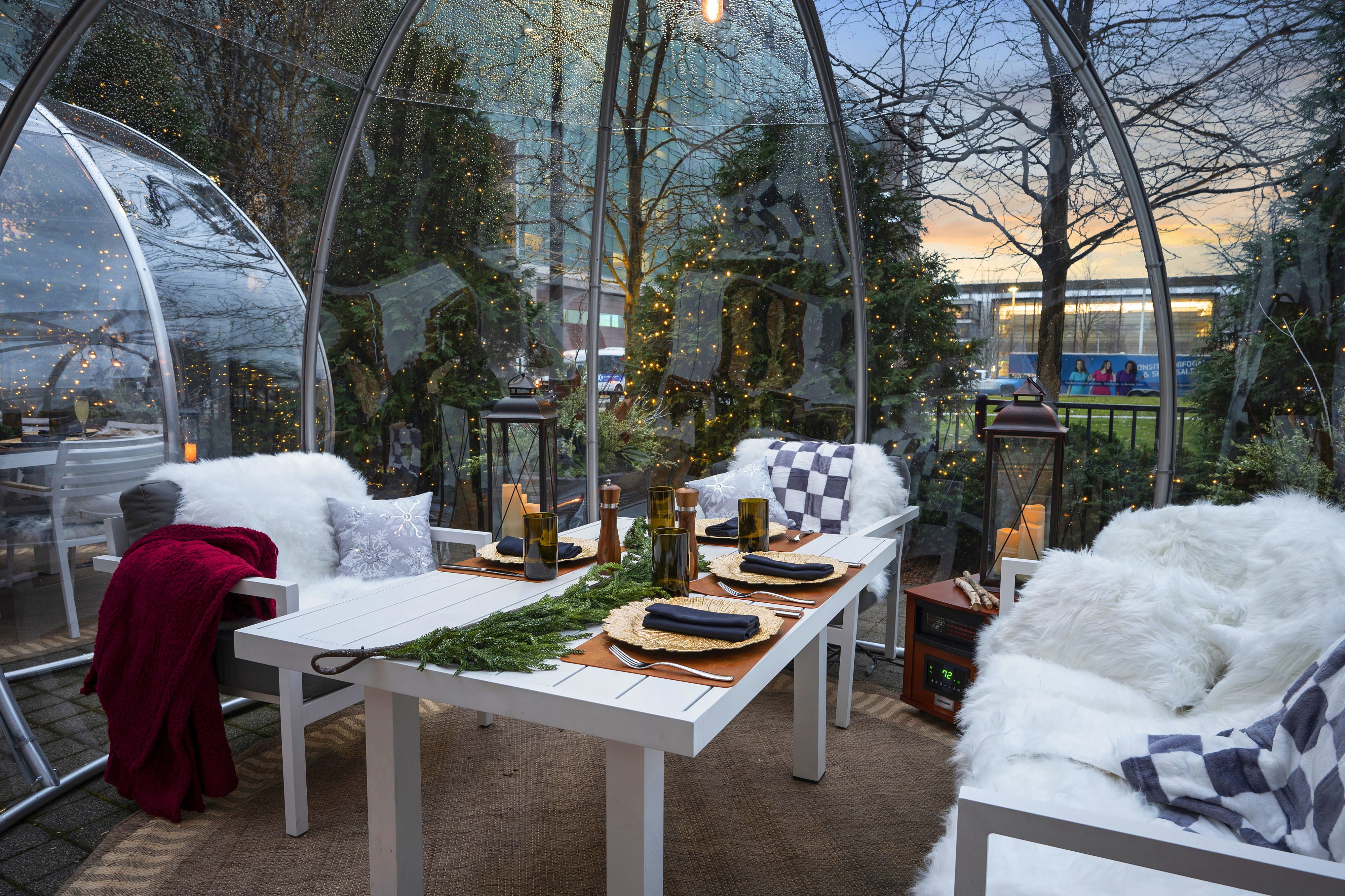Outdoor dining igloo with a set table and festive lights