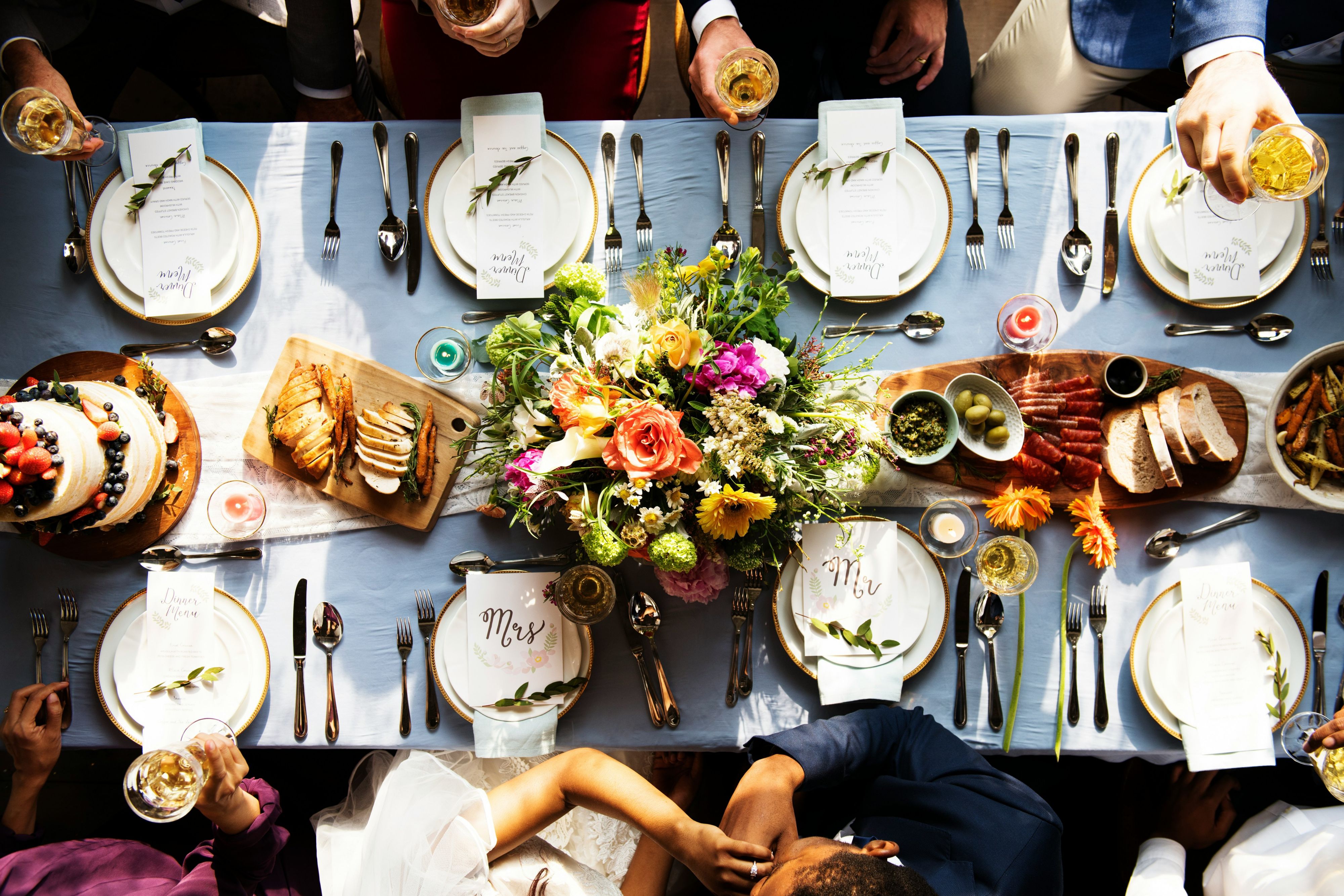 Overhead view of a long table set with shared dishes, flowers, and place settings.