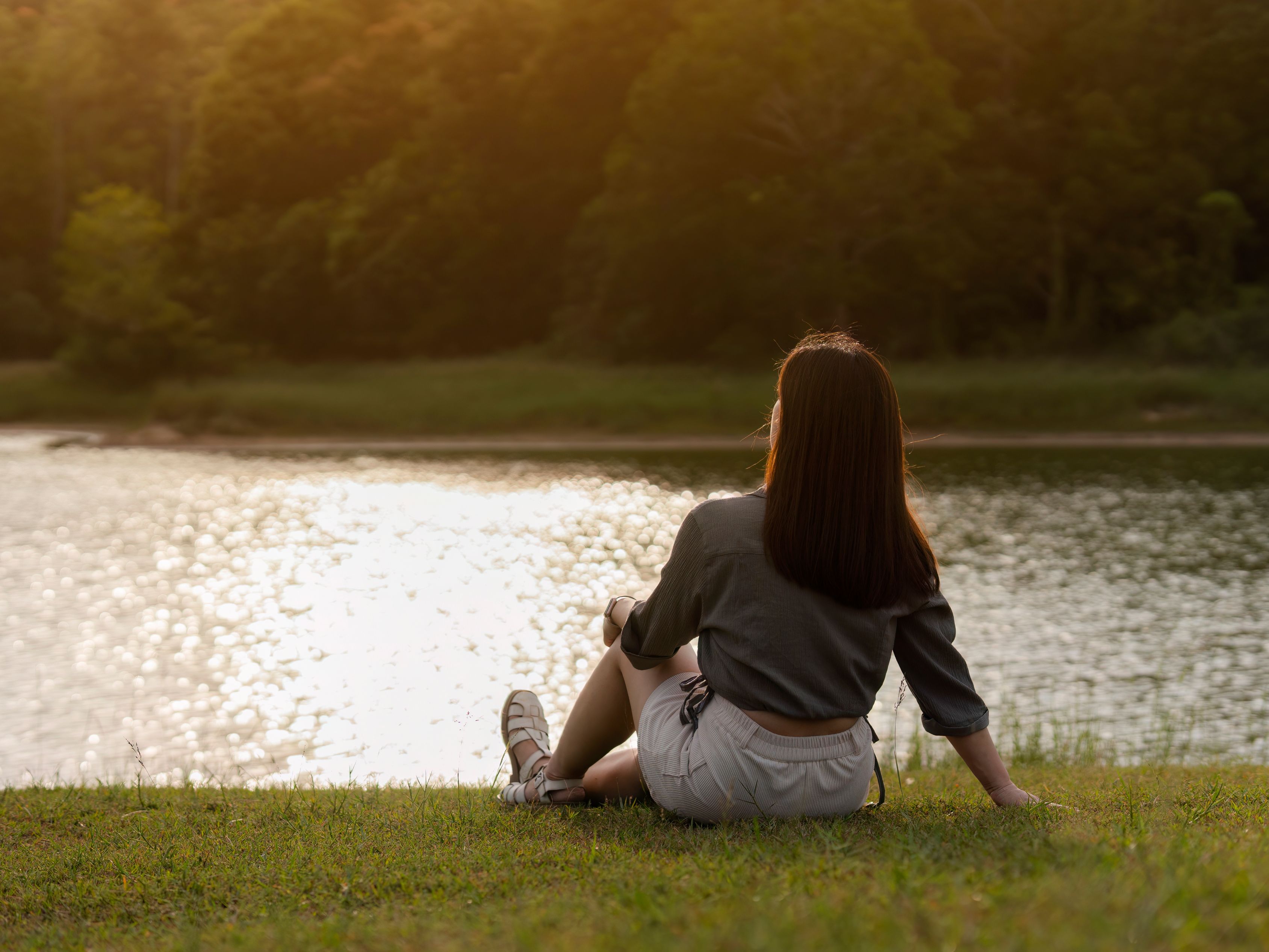 Woman sitting in front of water at park