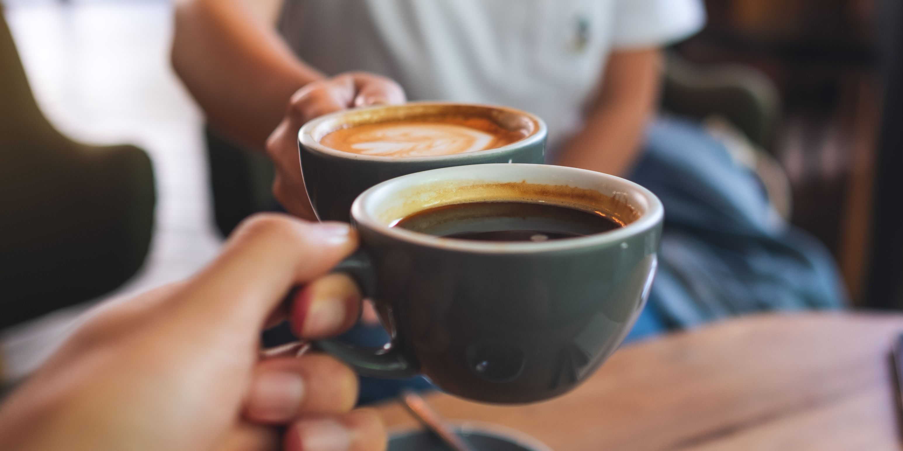 Friends cheersing with cups of coffee.