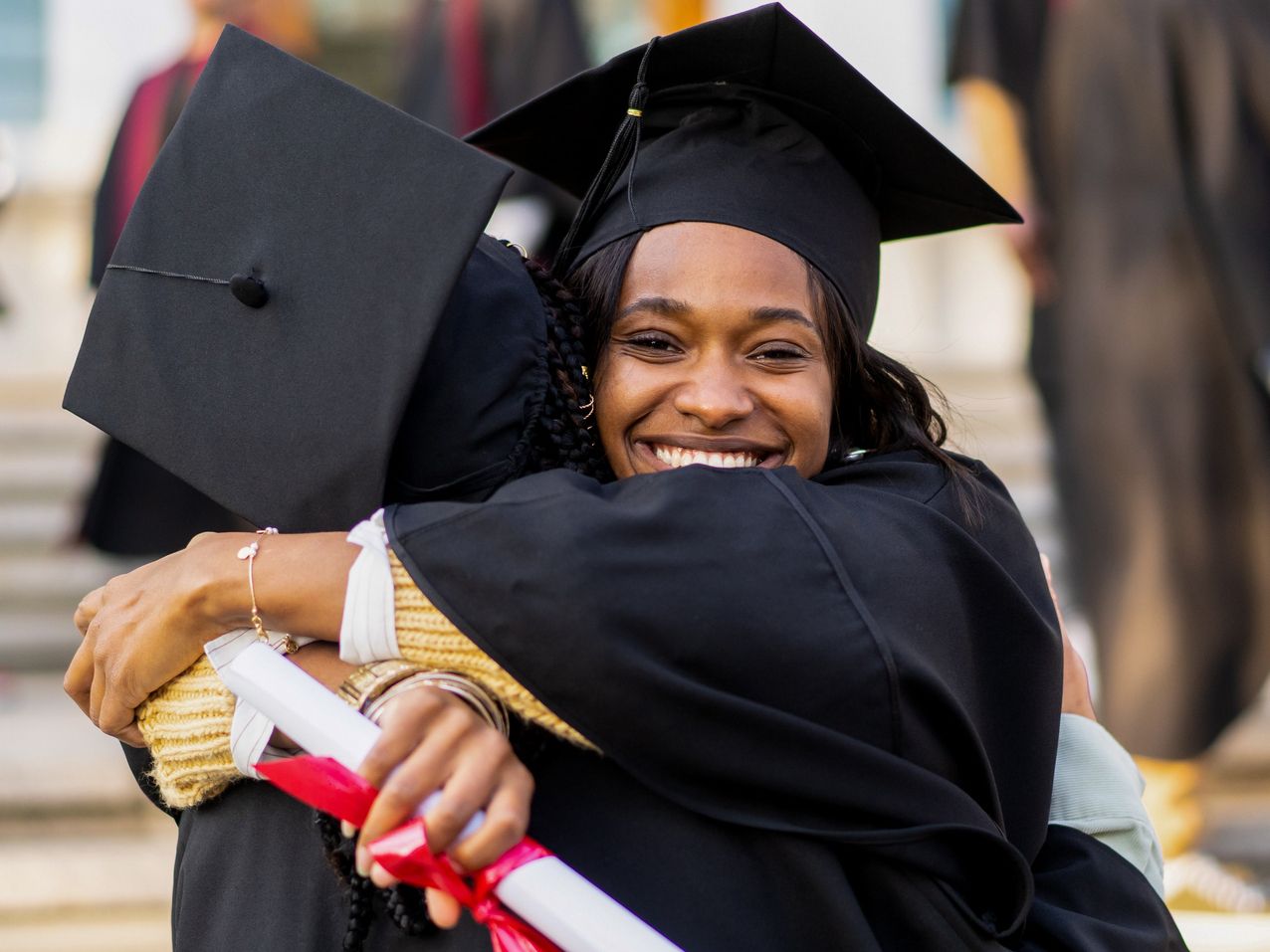 College graduates hugging.