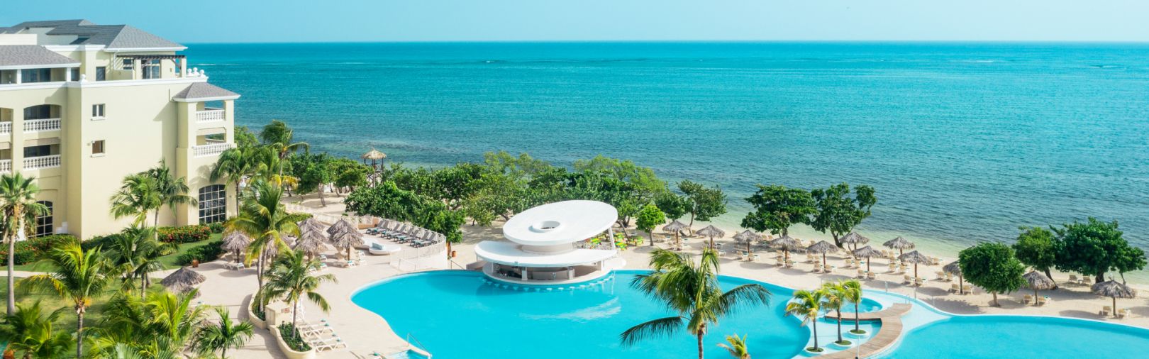 Beachfront resort with lagoon-style pools, palm trees, and ocean views. 