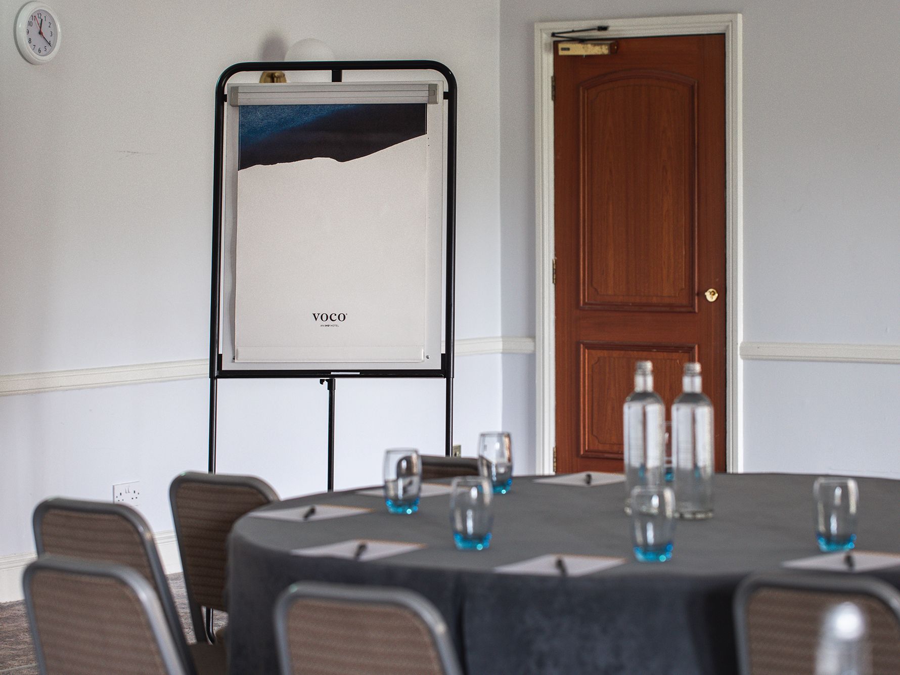Meeting room with table, stationery and presentation board with voco logo