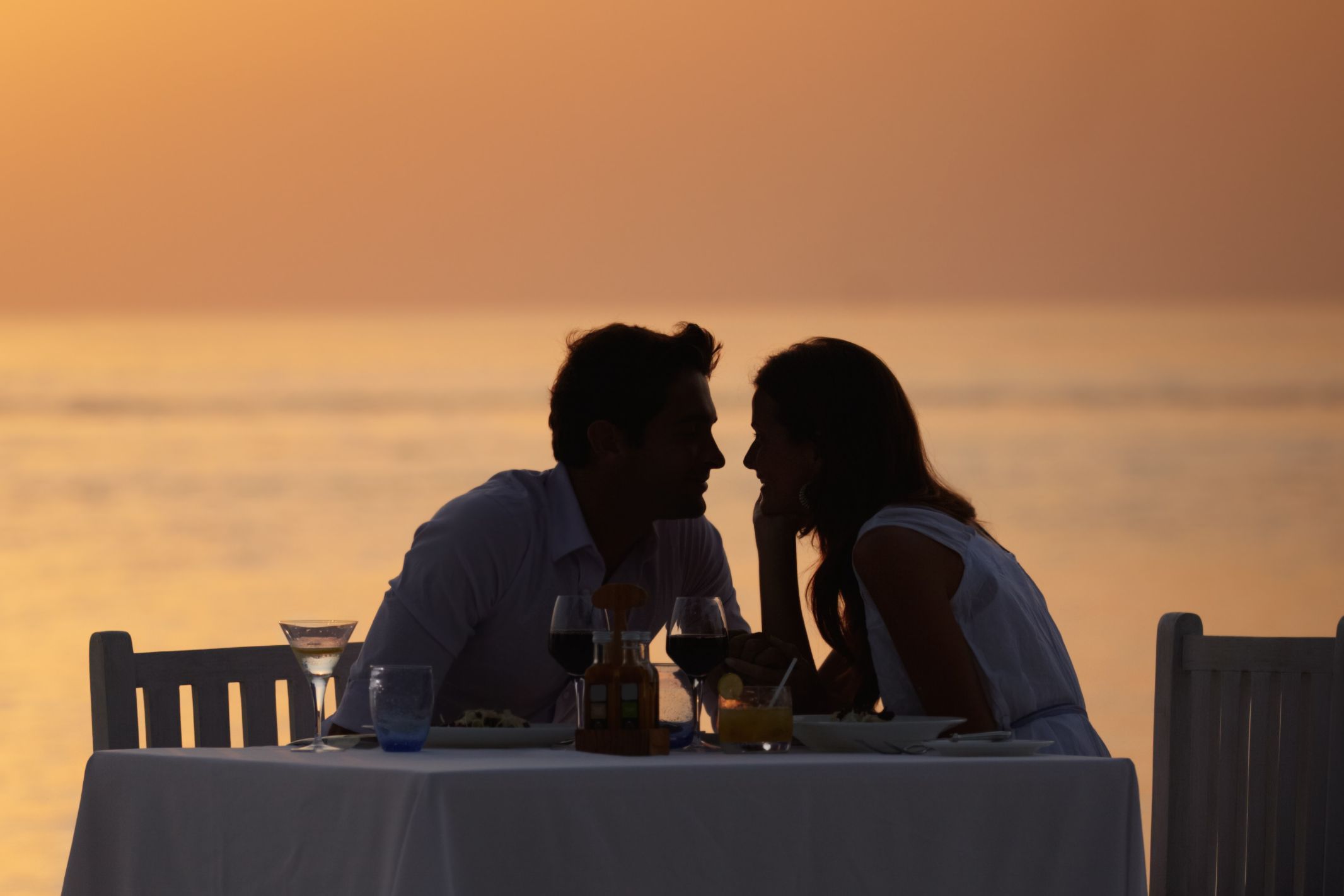 Pareja cenando en la playa durante el atardecer.