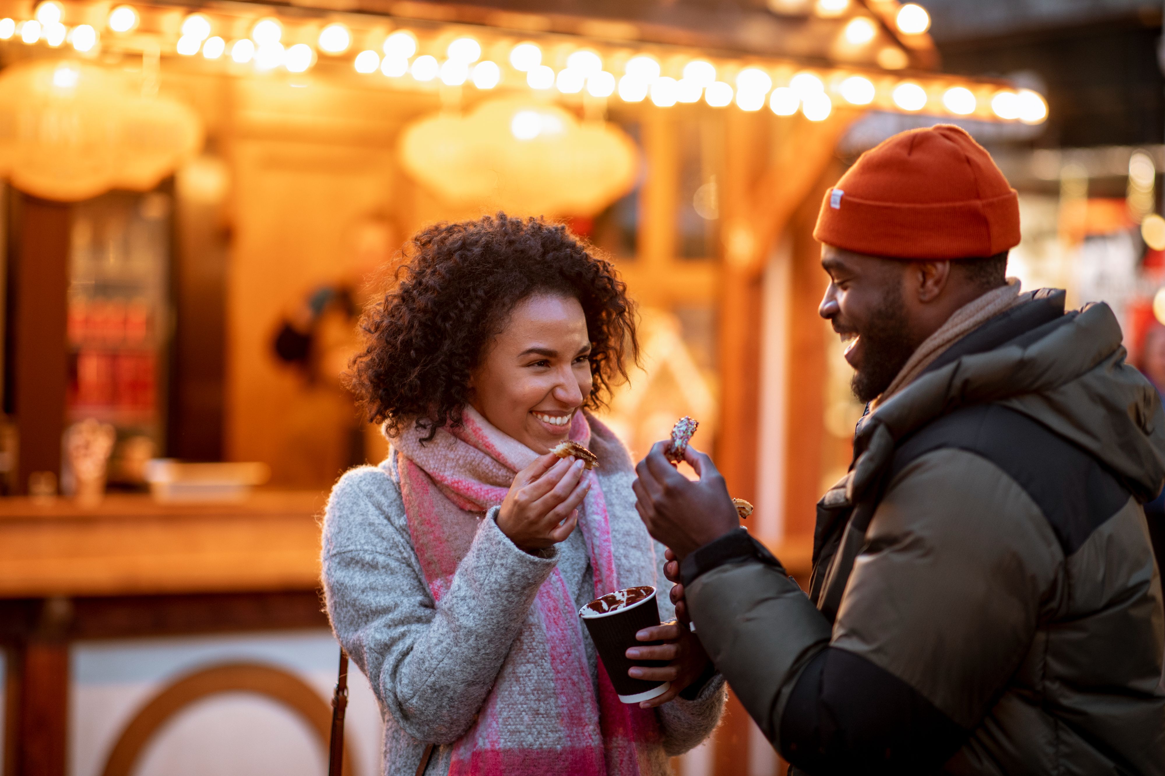 Couple enjoying hot chocolate at a holiday market.