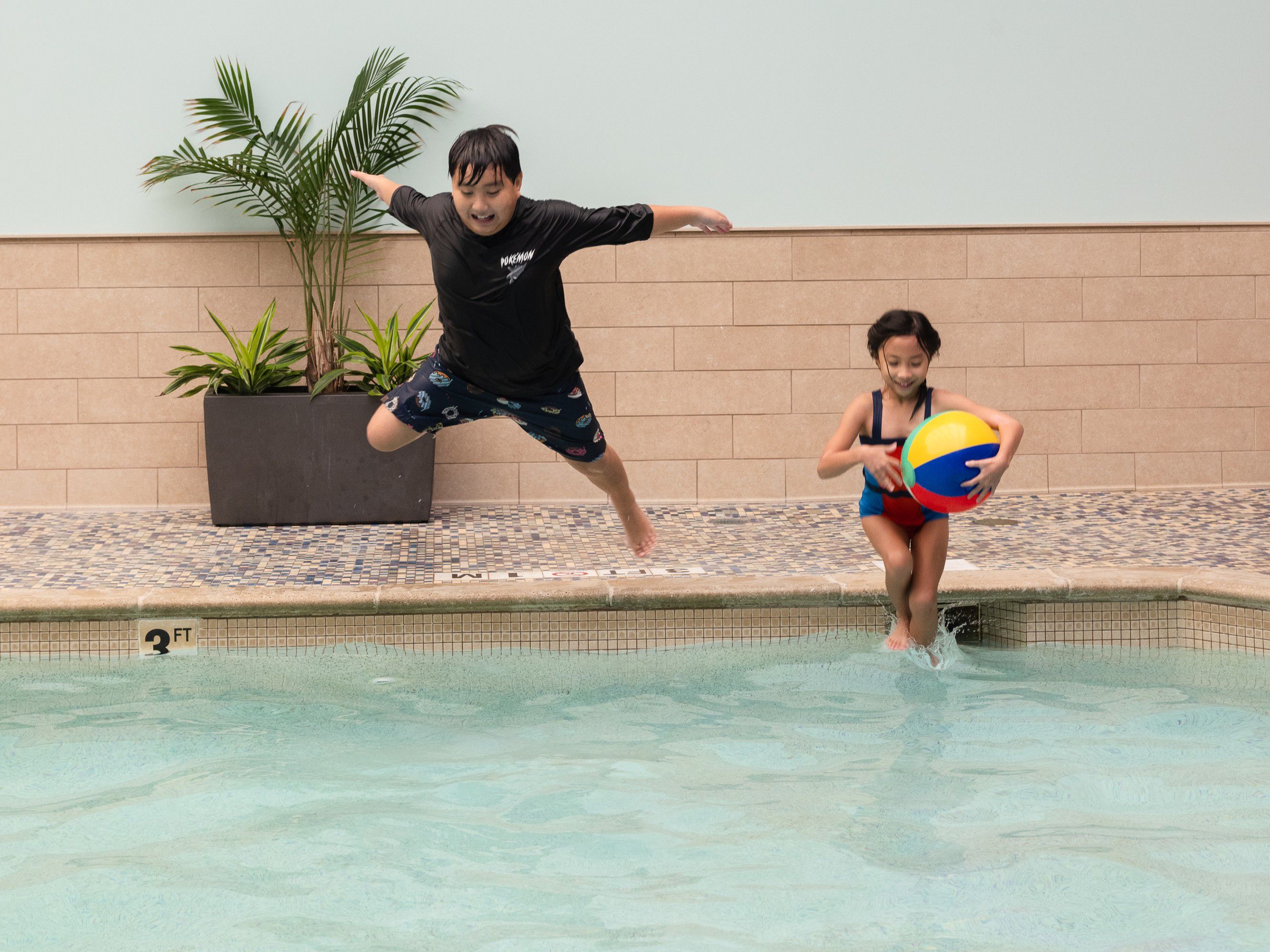 kids jumping in indoor pool smiling