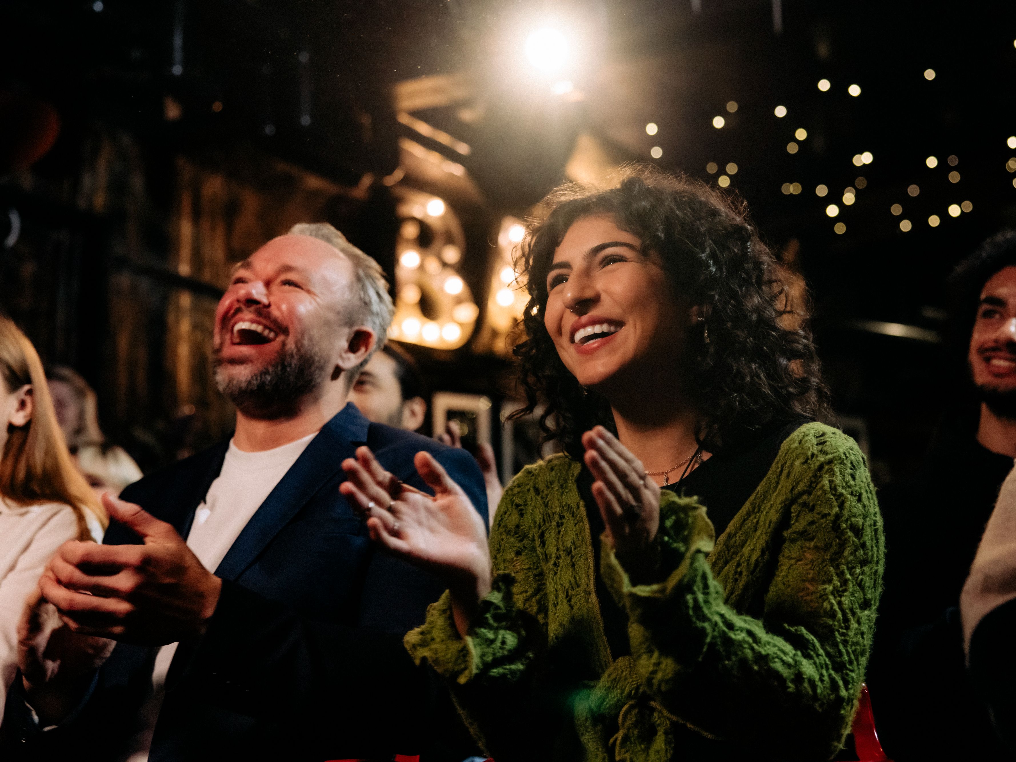 Crowd cheering and laughing at a comedy show.