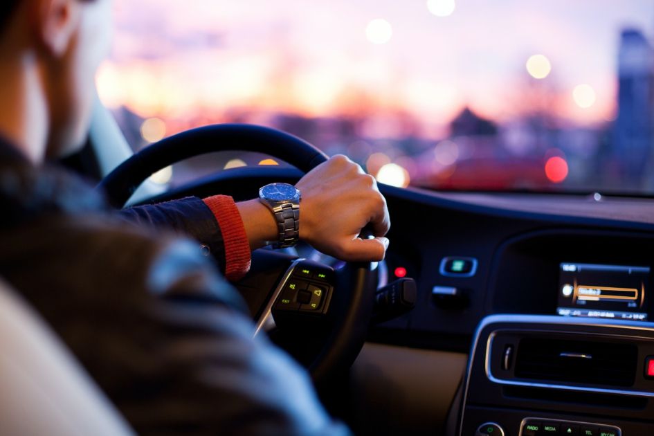 Hand on steering wheel of car