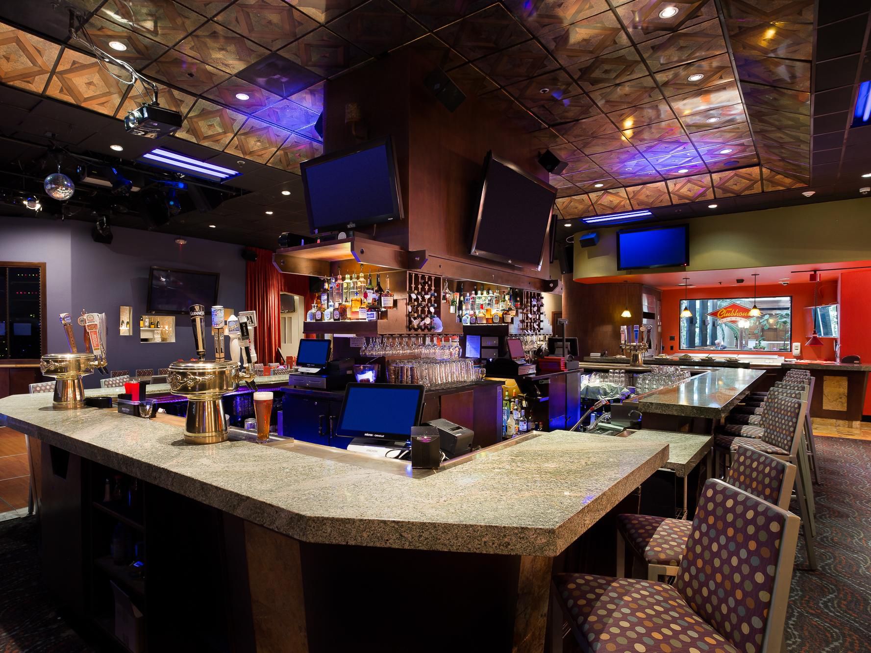 Hotel bar with granite counter, beer taps, and mounted TVs.
