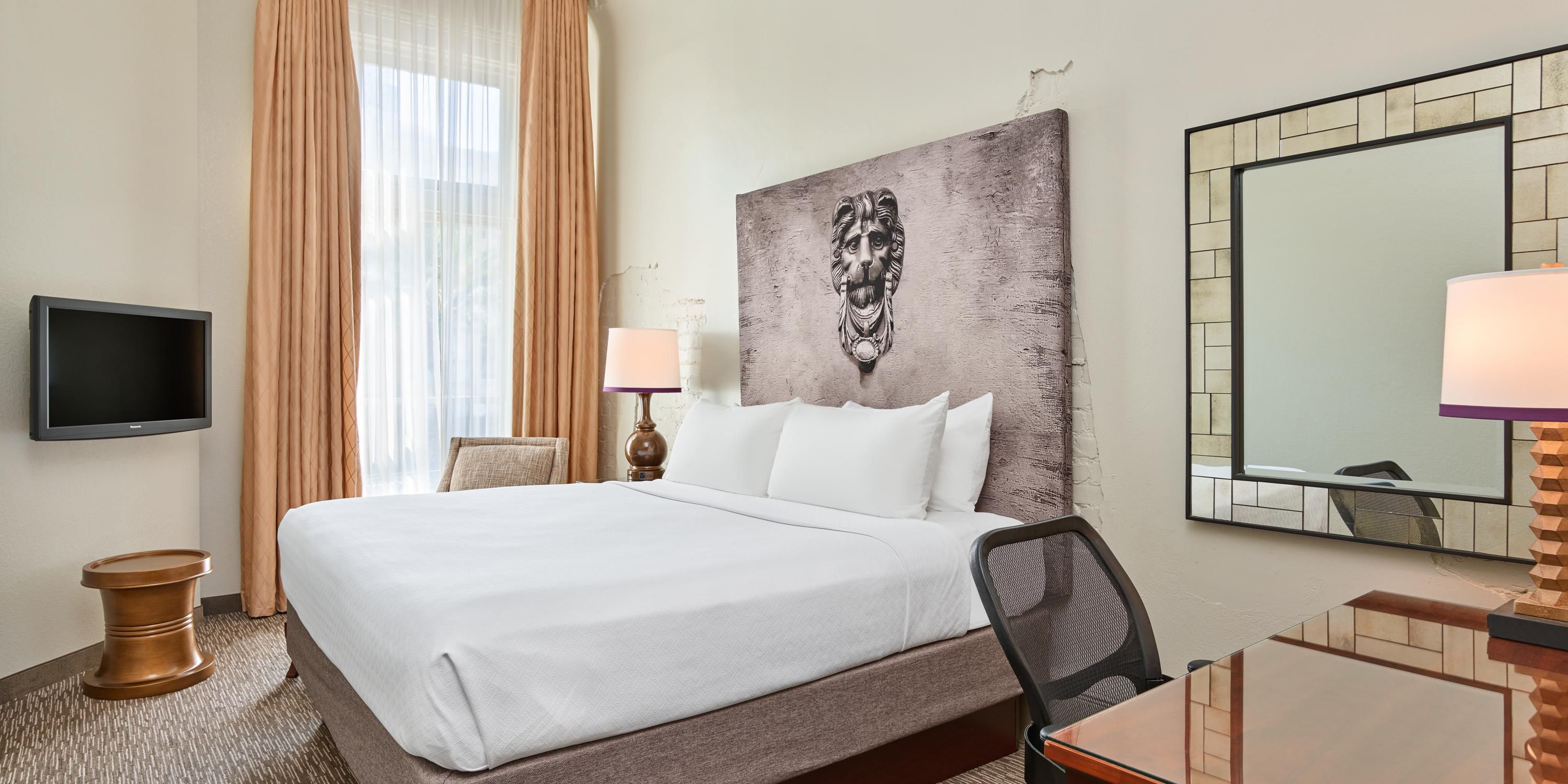 Hotel room with ornate headboard and desk.