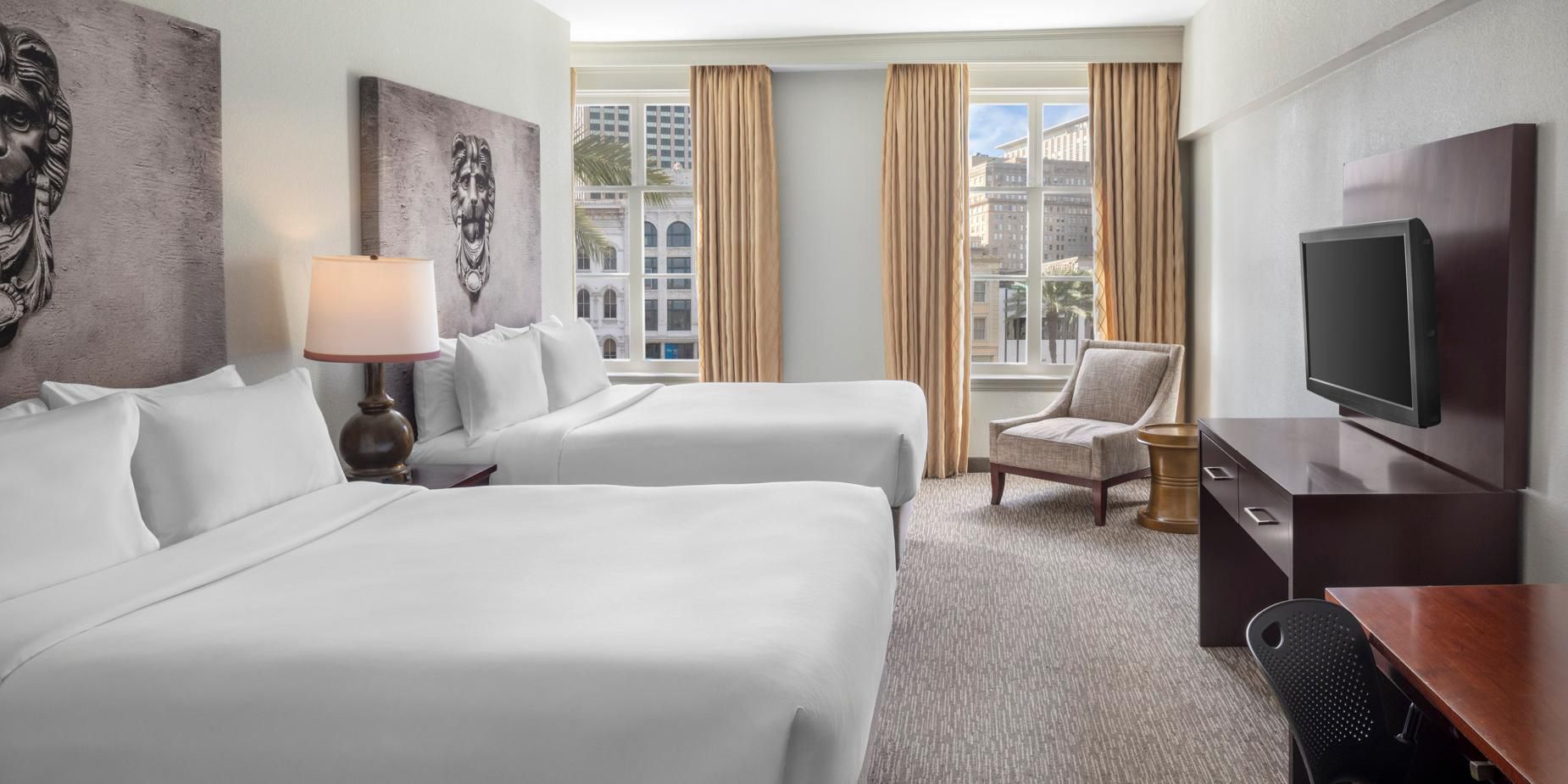 Standard queen hotel room with two beds, a desk, chair, and city view.