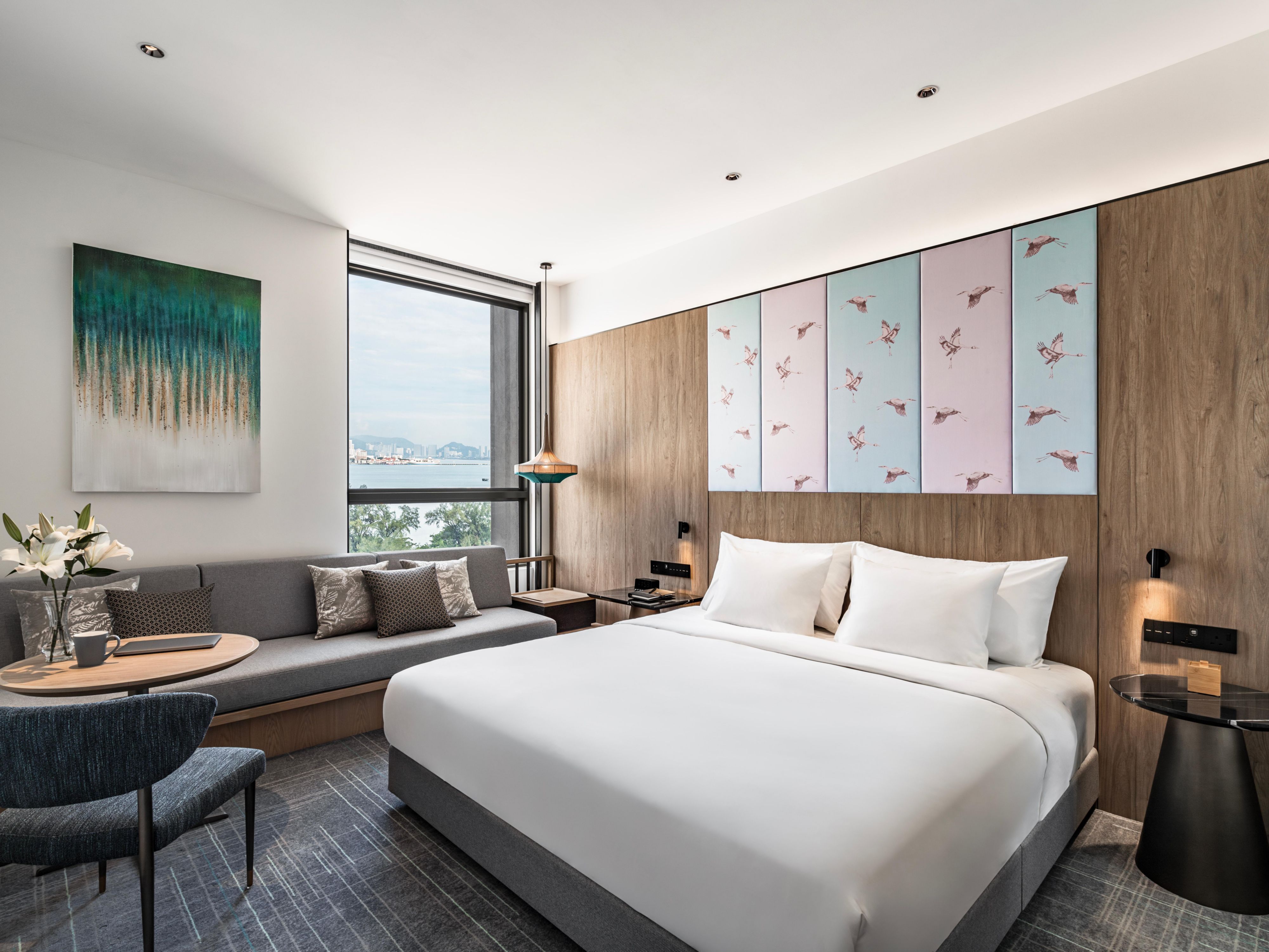 Elegante habitación con cama tamaño king, sofá cama y vista panorámica al mar.