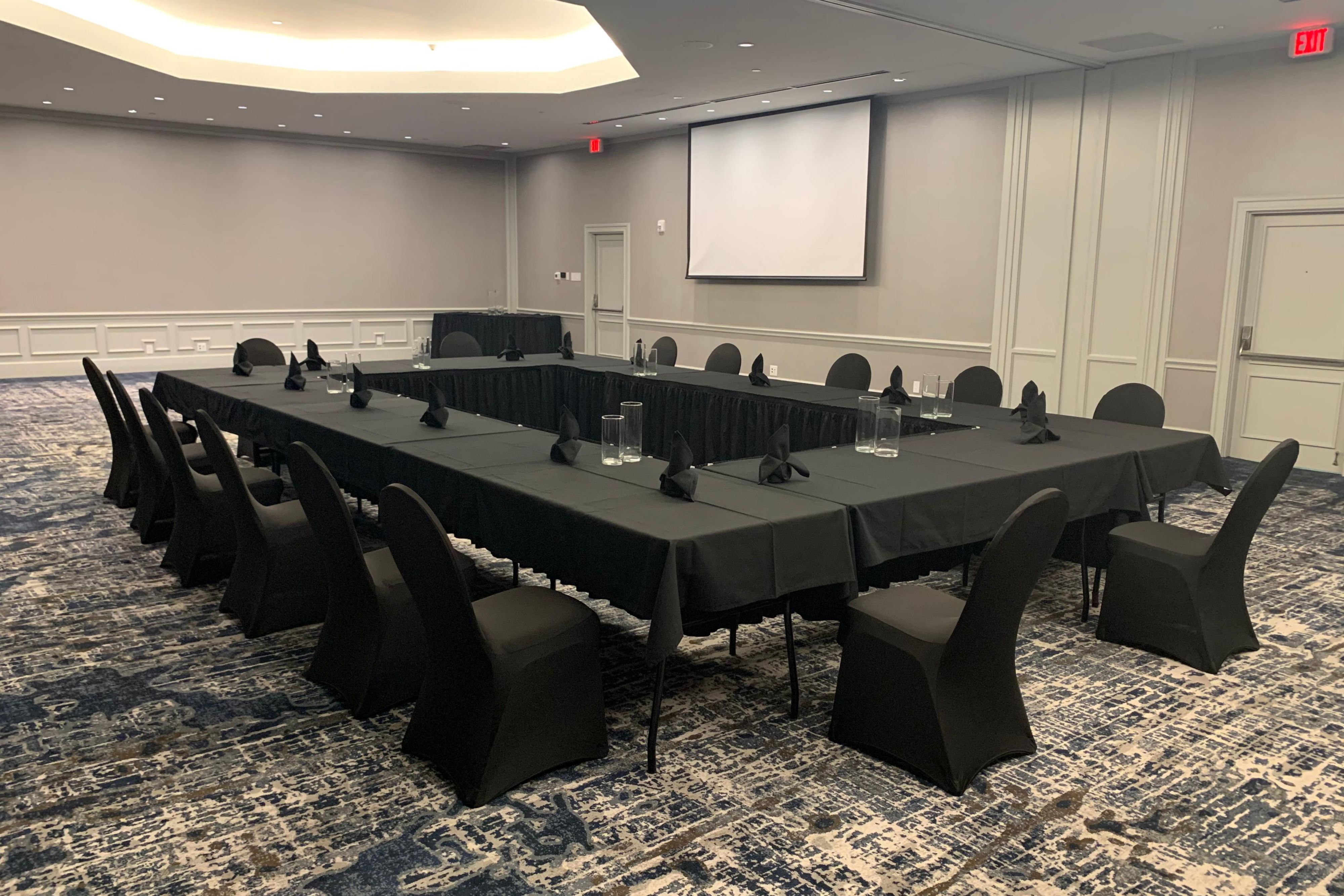 Meeting space that can accommodate a large group with long tables and white linens