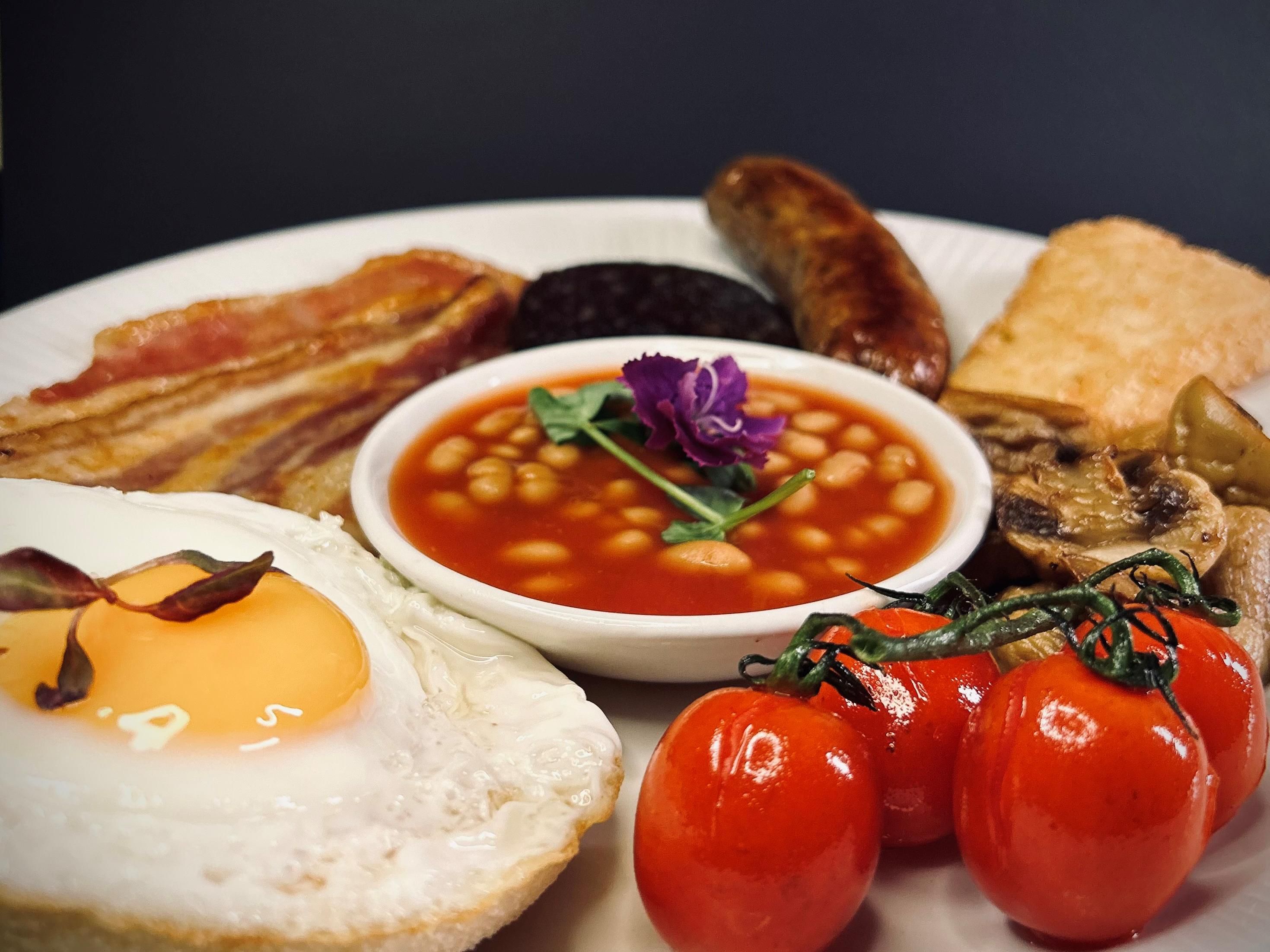 ソーセージ、ベーコン、豆類、マッシュルーム、トマト、ハッシュブラウンなどの英国の伝統料理を取り揃えたおいしい朝食ビュッフェをお楽しみください。卵料理はリクエストに応じてご用意しております。新鮮＆ドライフルーツ入りヨーグルト、サワードウ、マルチグレインなど、チーズ、コールドカット、ペーストリー、ジャム、ジュース、デトックス＆シナモンウォーターが含まれています。