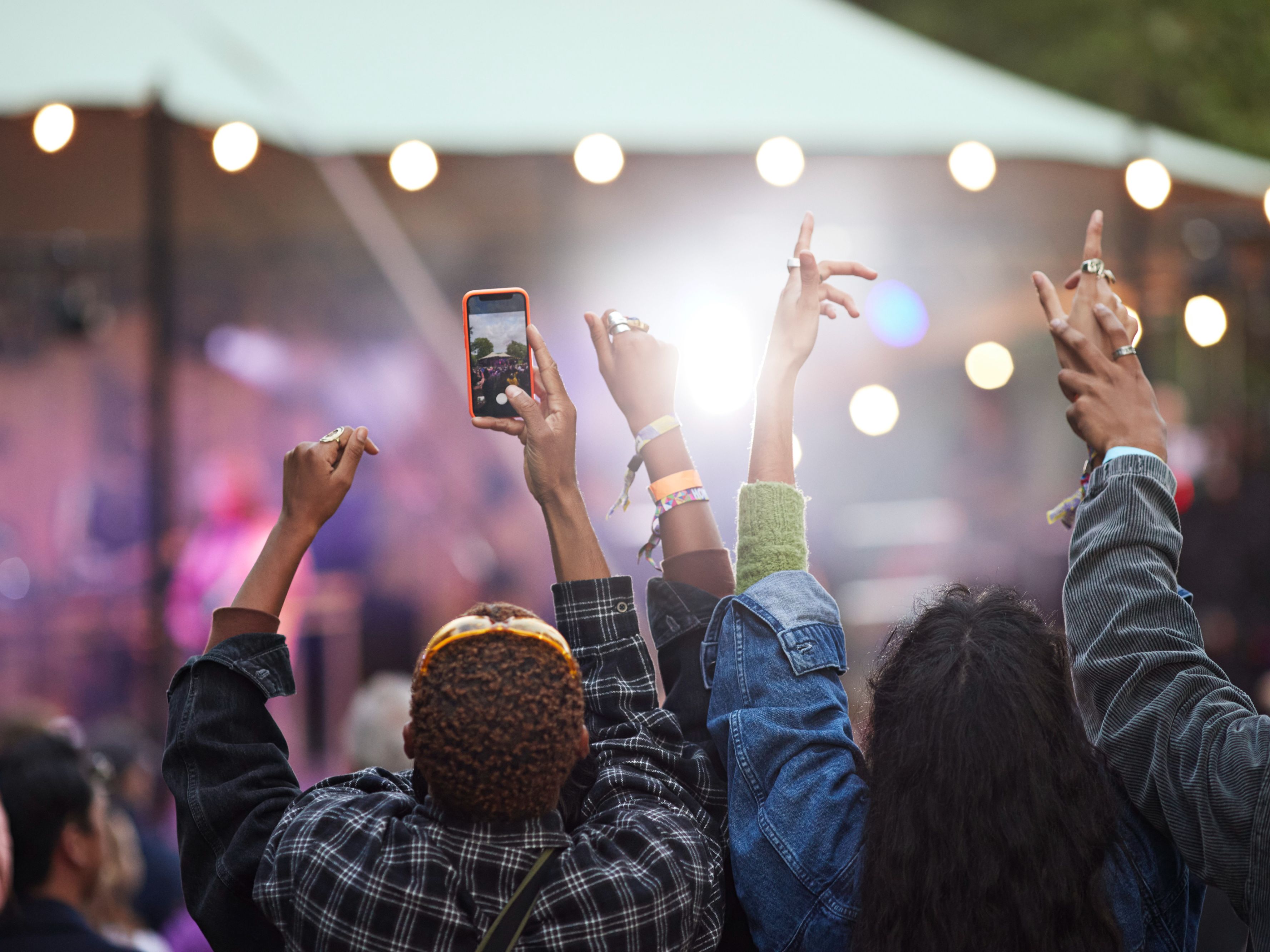 Group of friends enjoying an outdoor concert and taking videos.