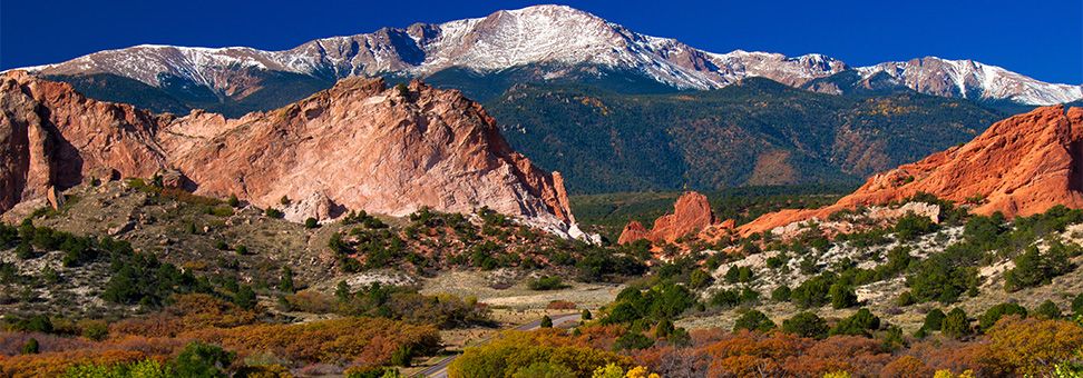 View of snowy peak of Pikes Peak and red sandstone hills in the foreground