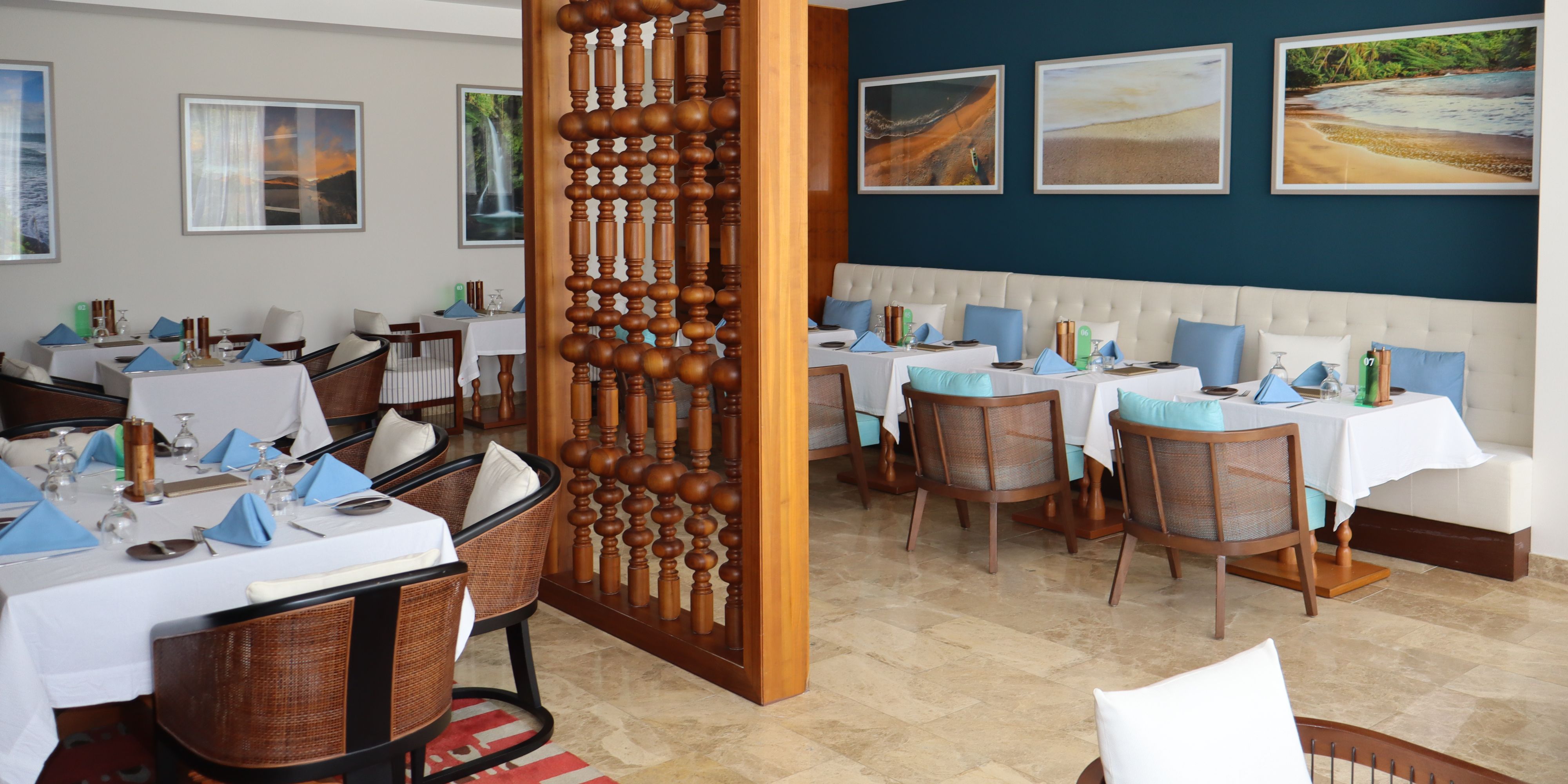 Wide view of Saltwood restaurant showcasing contemporary coastal décor, white table settings, blue accents, and spacious seating for breakfast, lunch, or dinner.