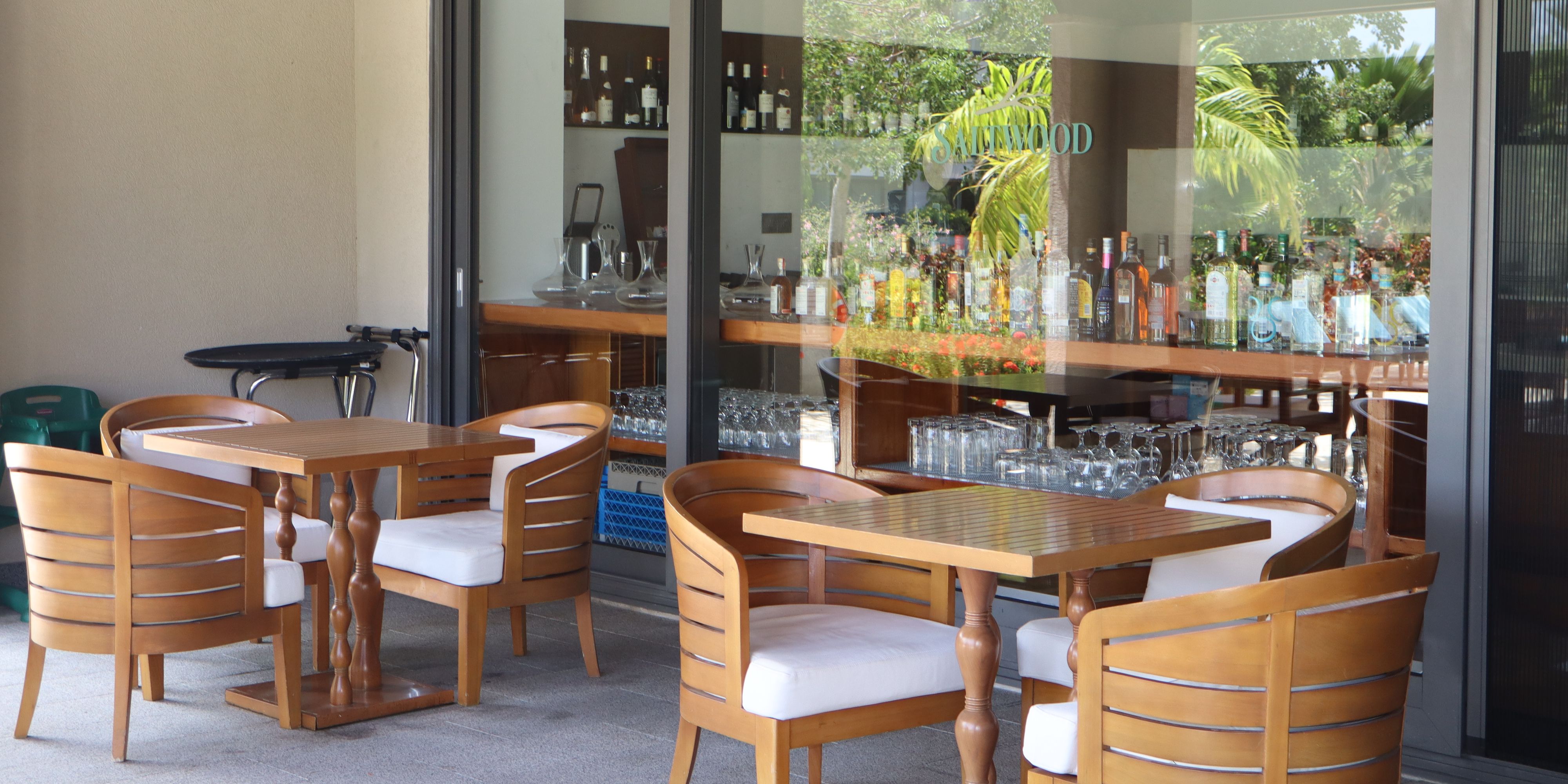 Outdoor dining terrace at Saltwood restaurant featuring wood furnishings, garden views, and convenient access to the restaurant’s bar and indoor dining area.