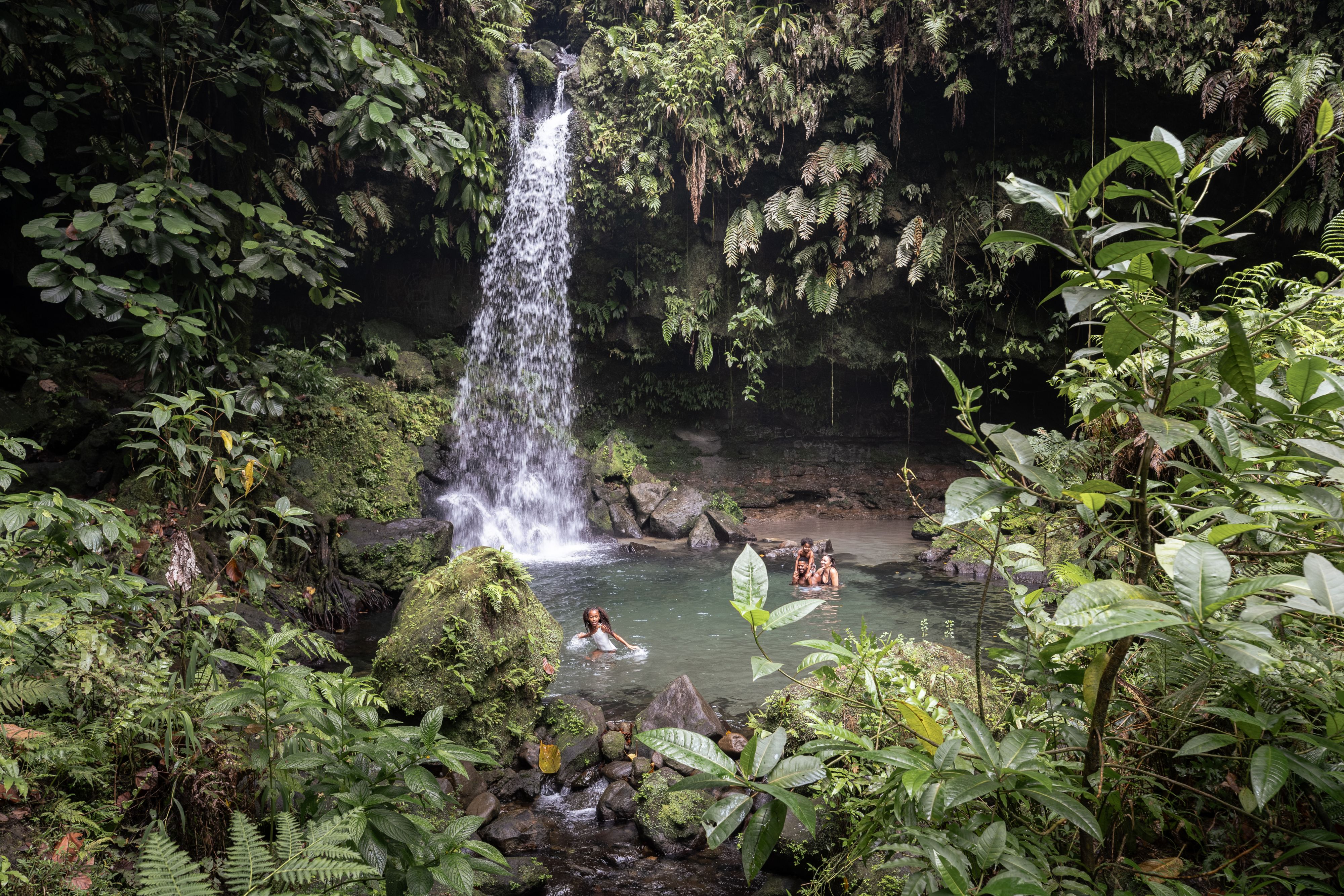 a group of people at the bottom of a waterfall in dominica