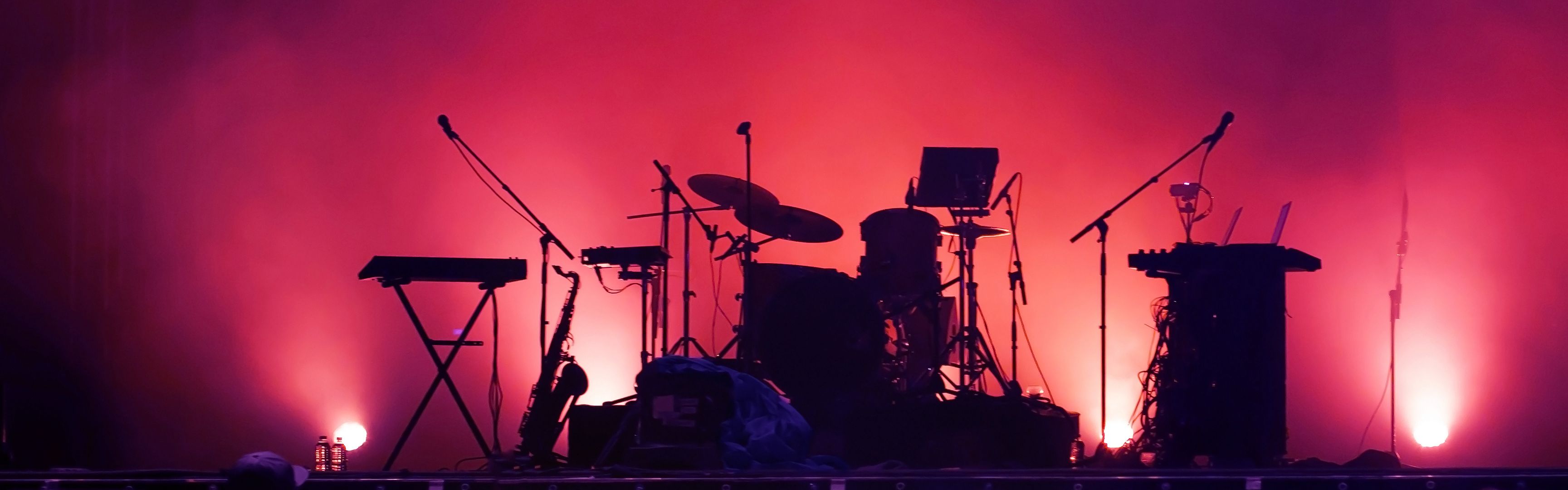 Drum kit on concert stage with sunset lighting.