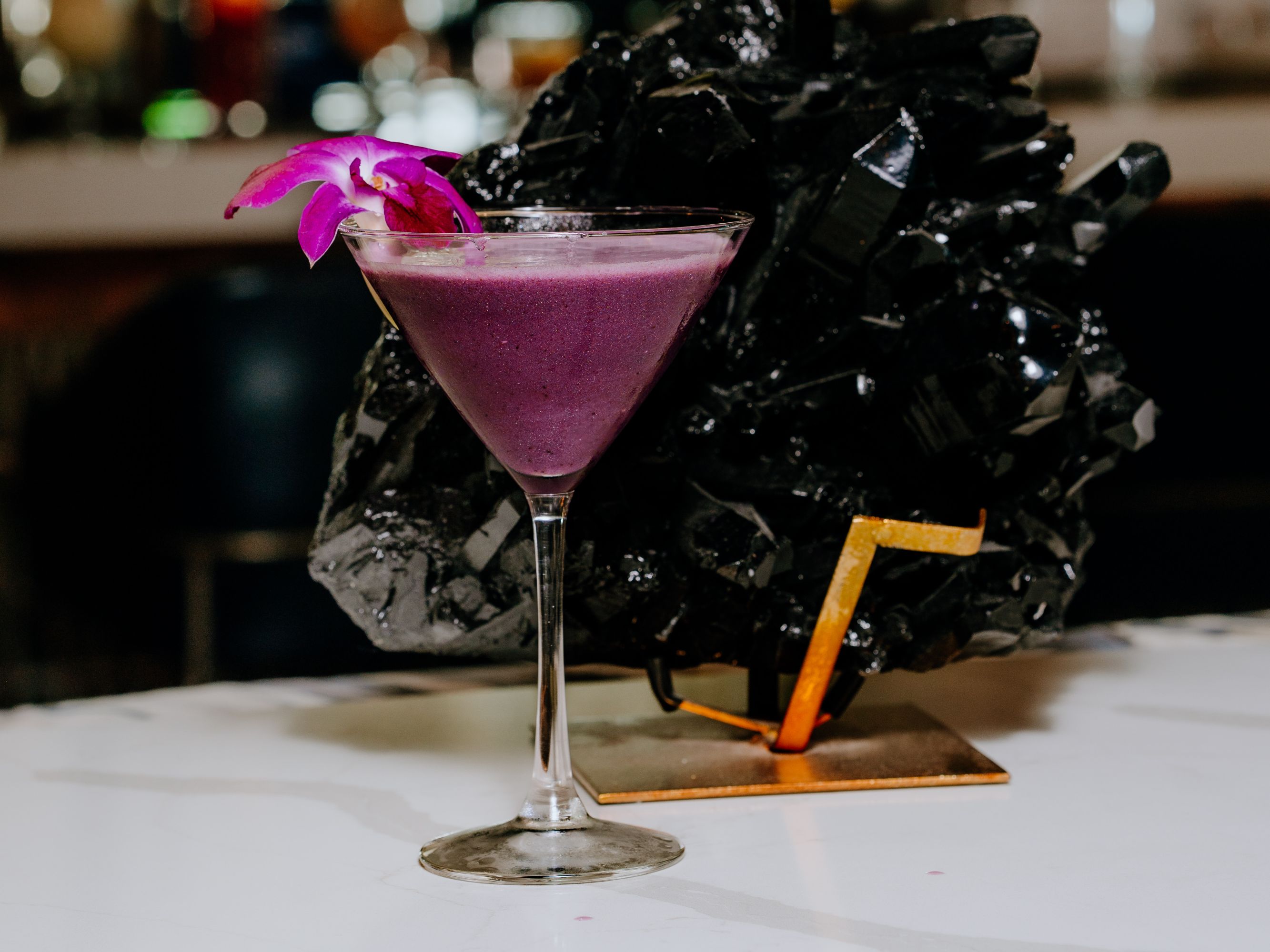 Purple cocktail with a flower garnish.