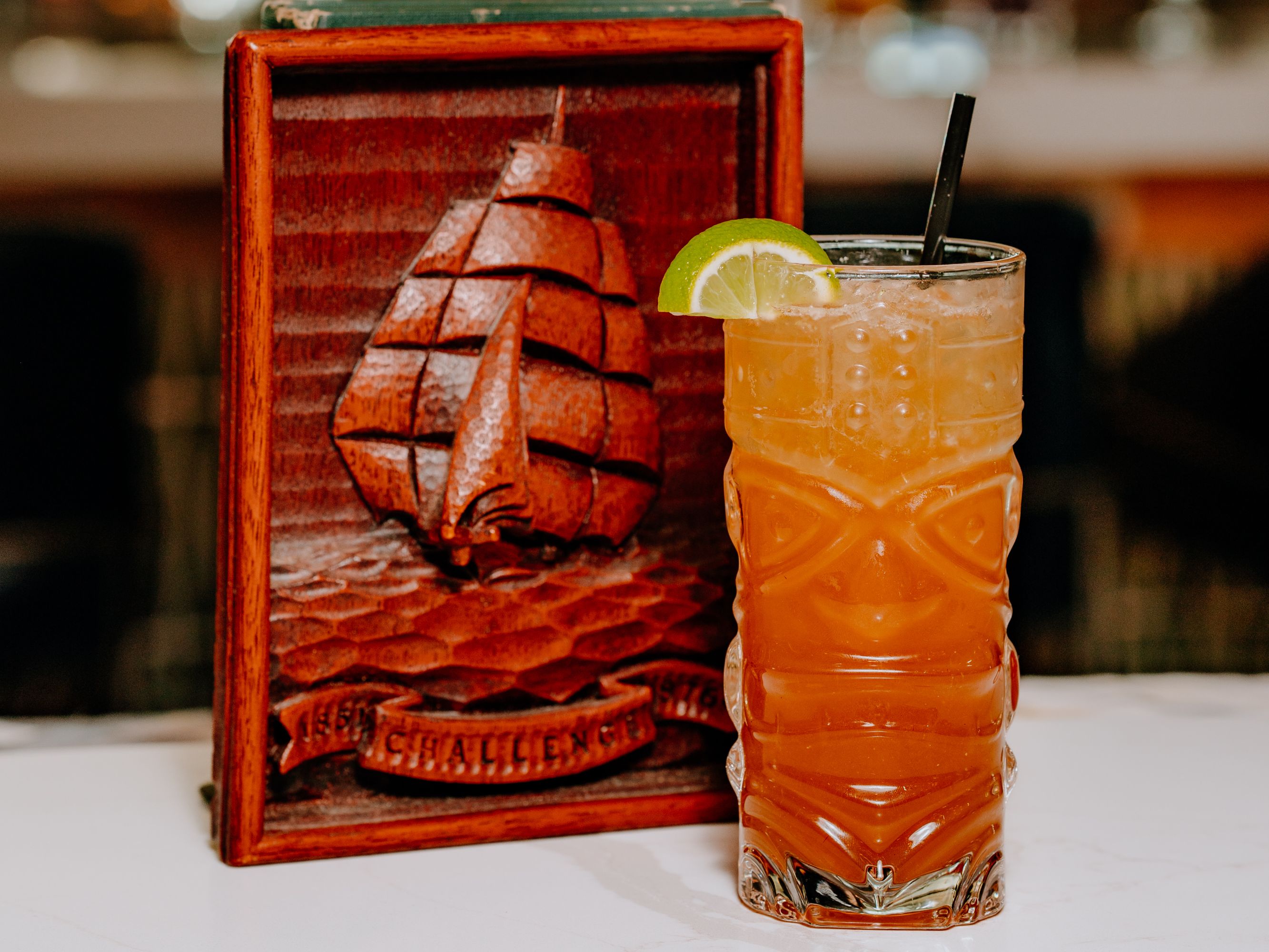 Cocktail with a lime with ship decor behind it.