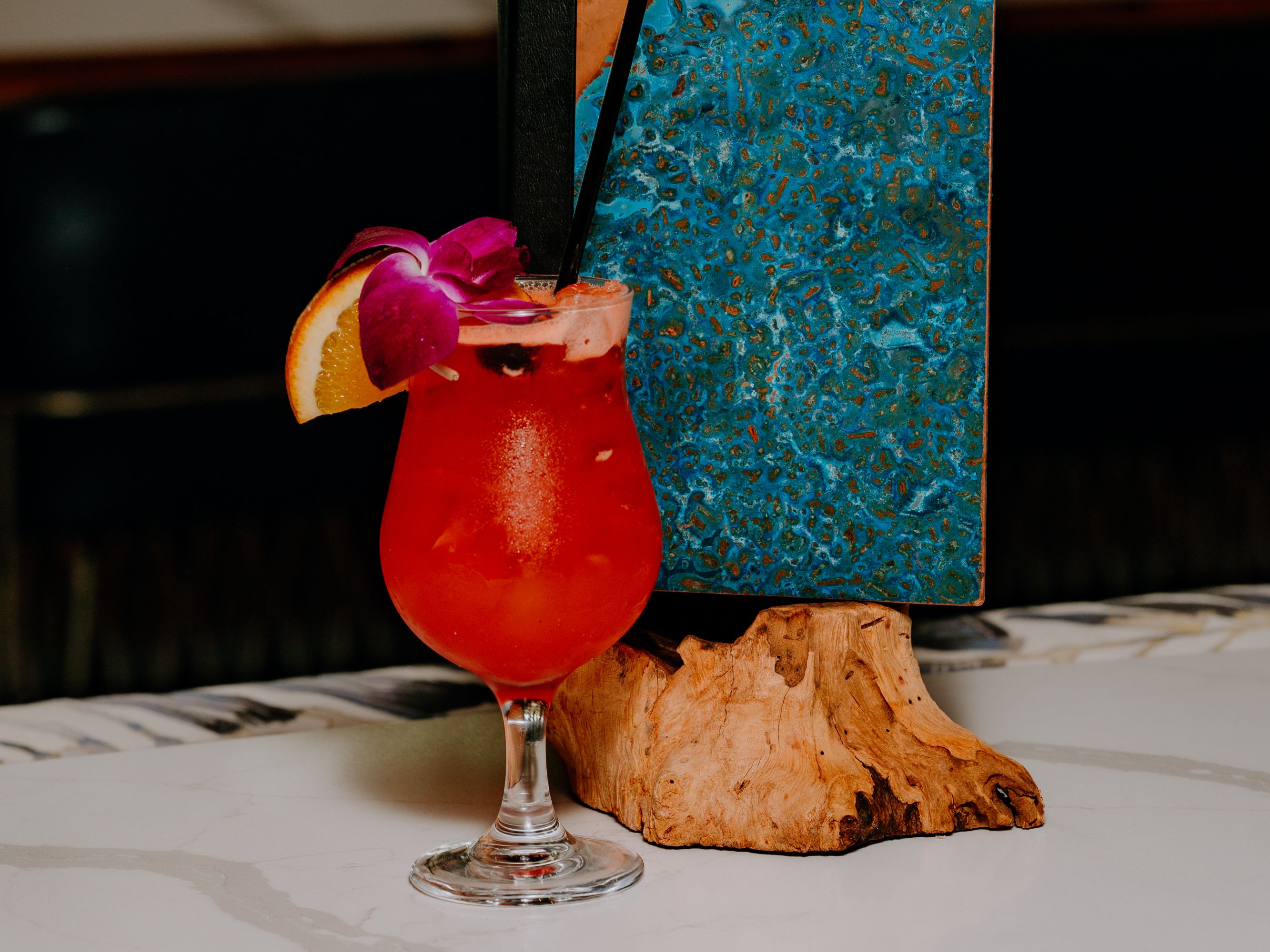 Cocktail garnished with fruit and a flower.