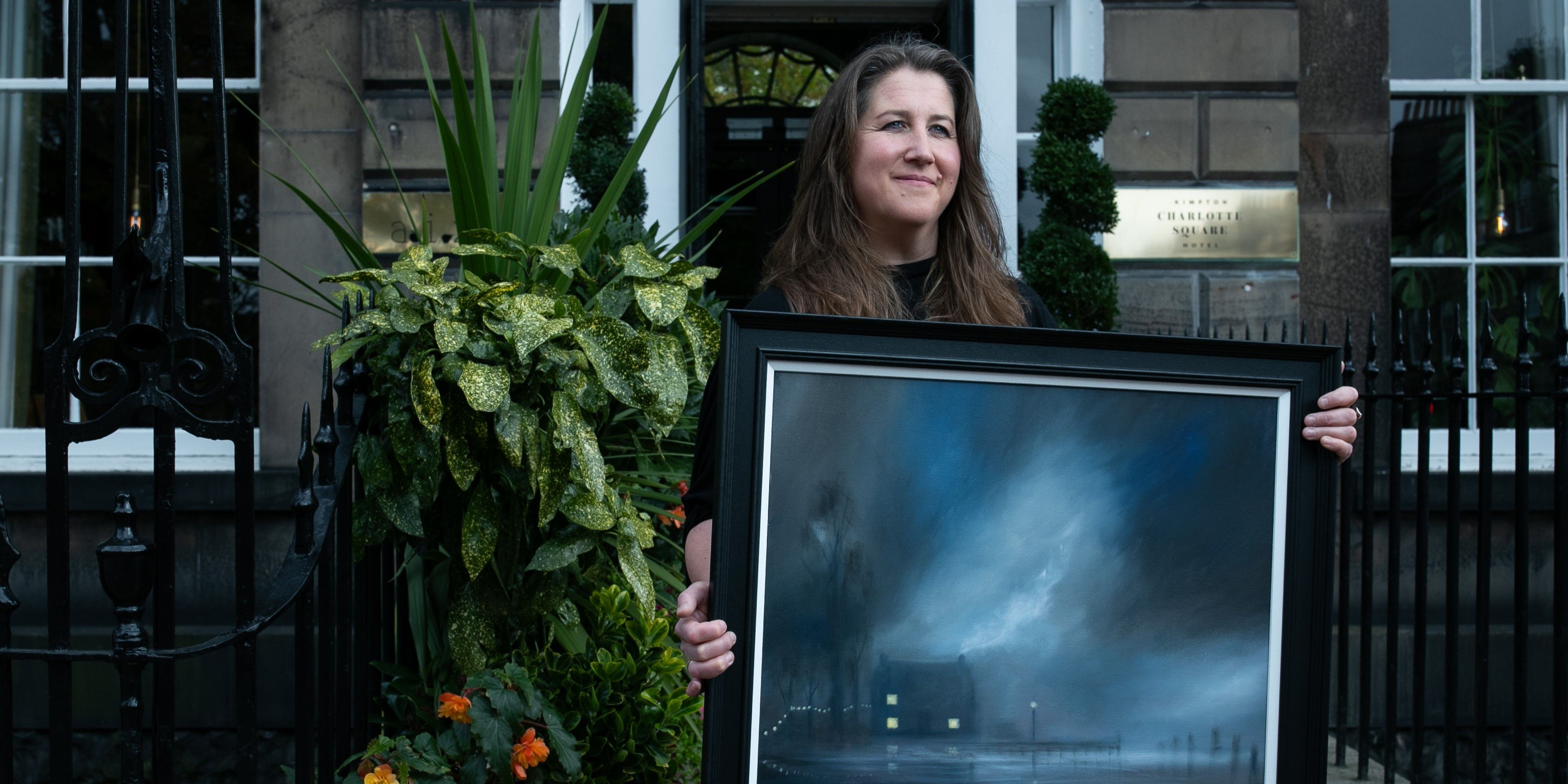Gill Knight holding up a painting
