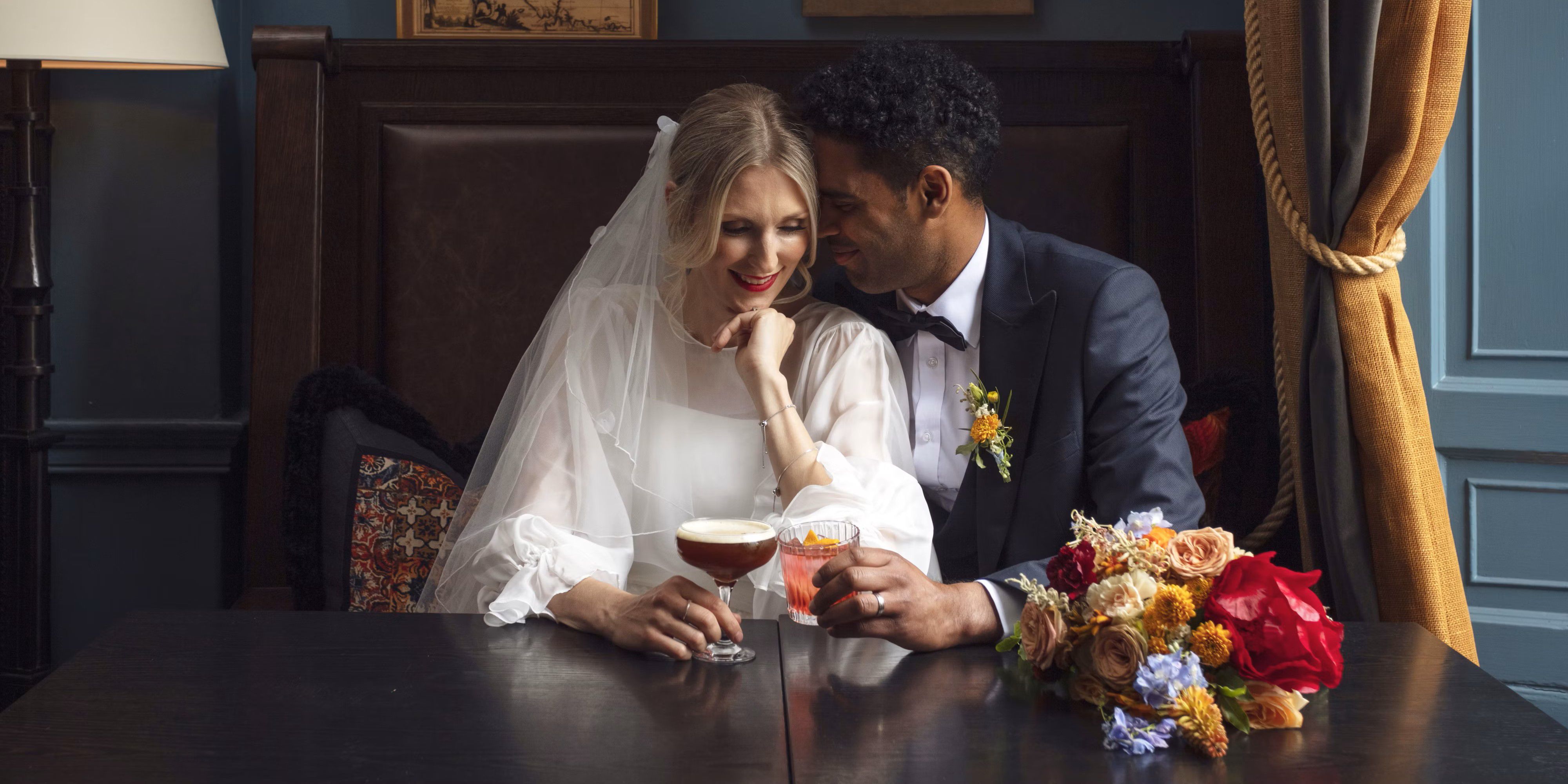 Bride and groom embracing with drinks on wedding day