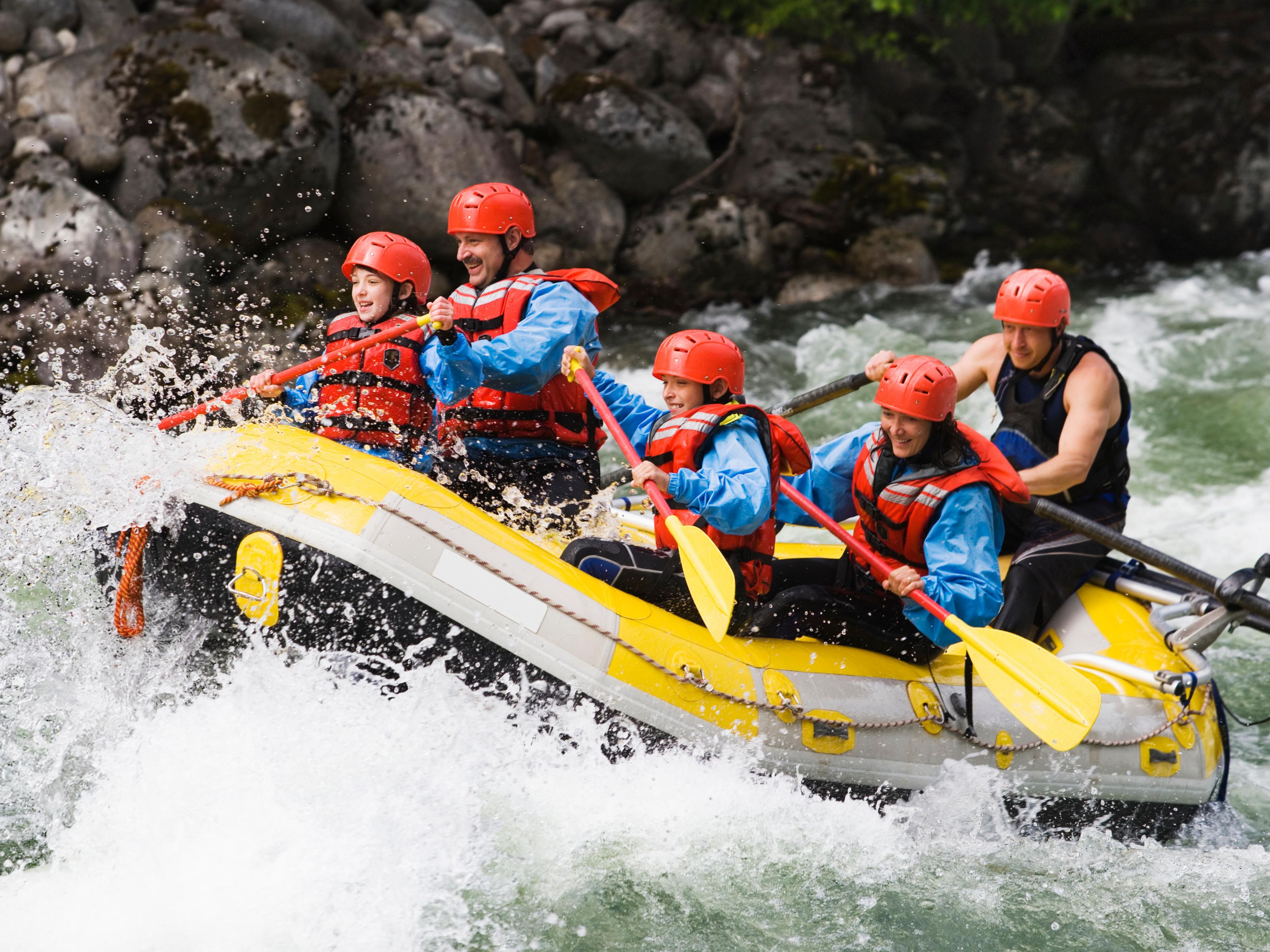 A group with paddles in a raft trying to navigate the rapids