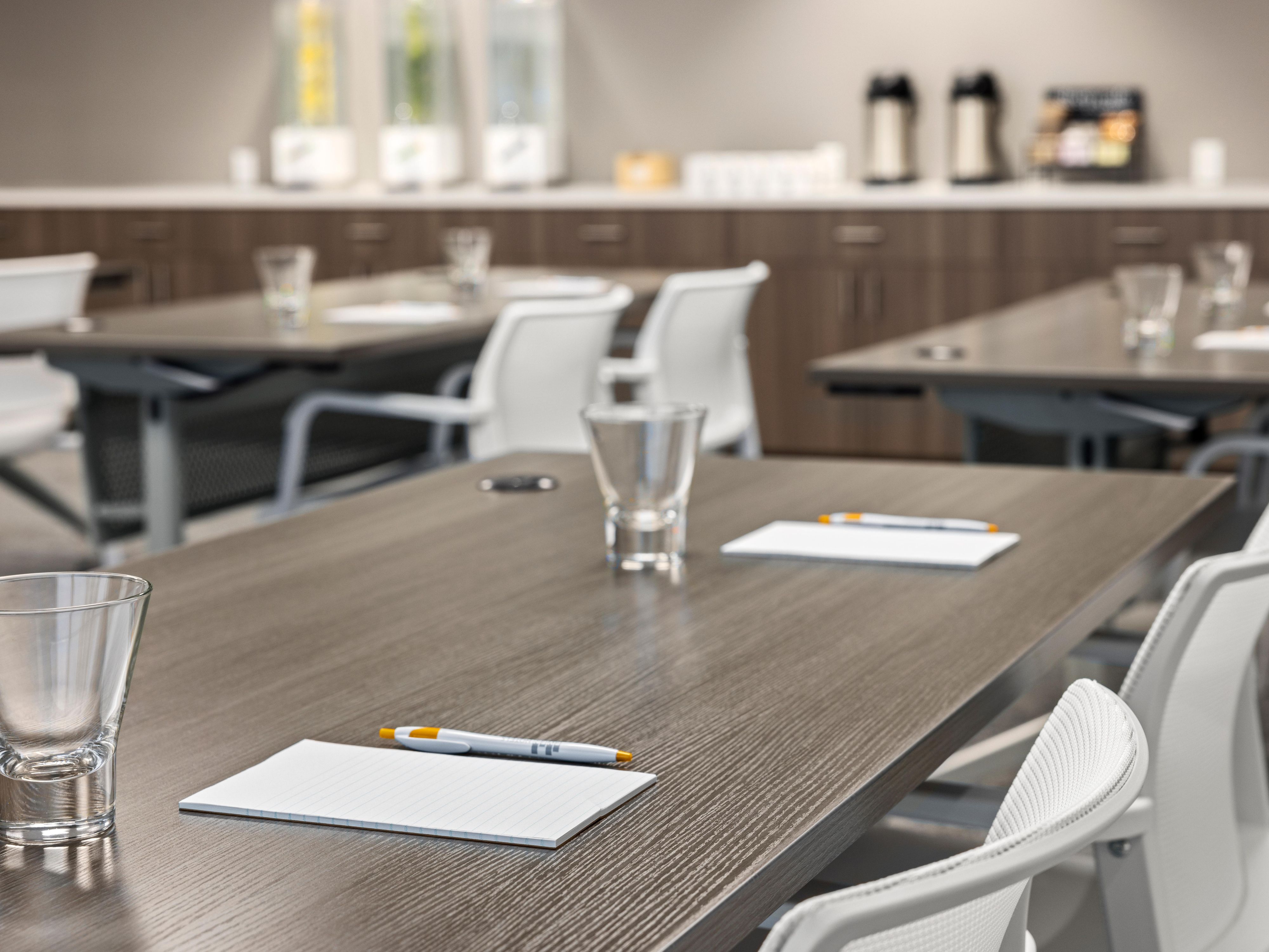 Meeting room desk with pens, notepads, and drinking glasses