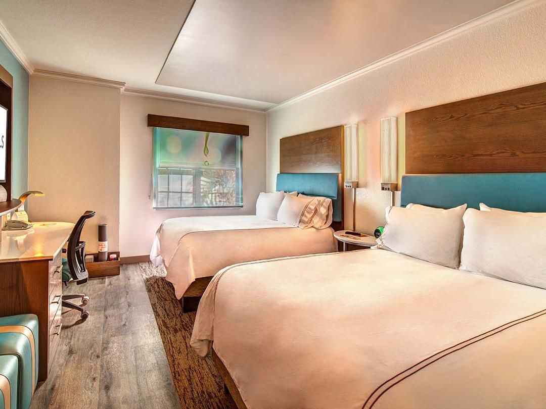 Two queen beds and a desk in a hotel room