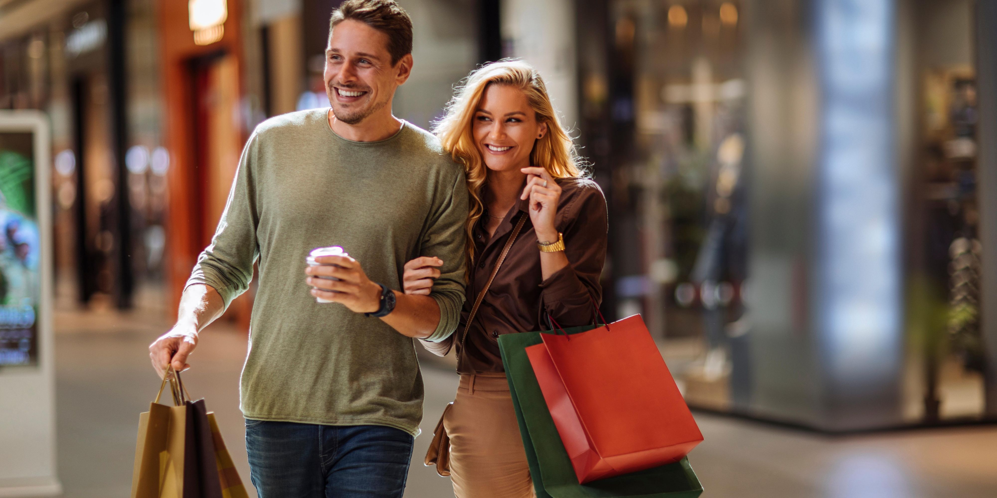 Couple shopping at the mall holding bags and smiling