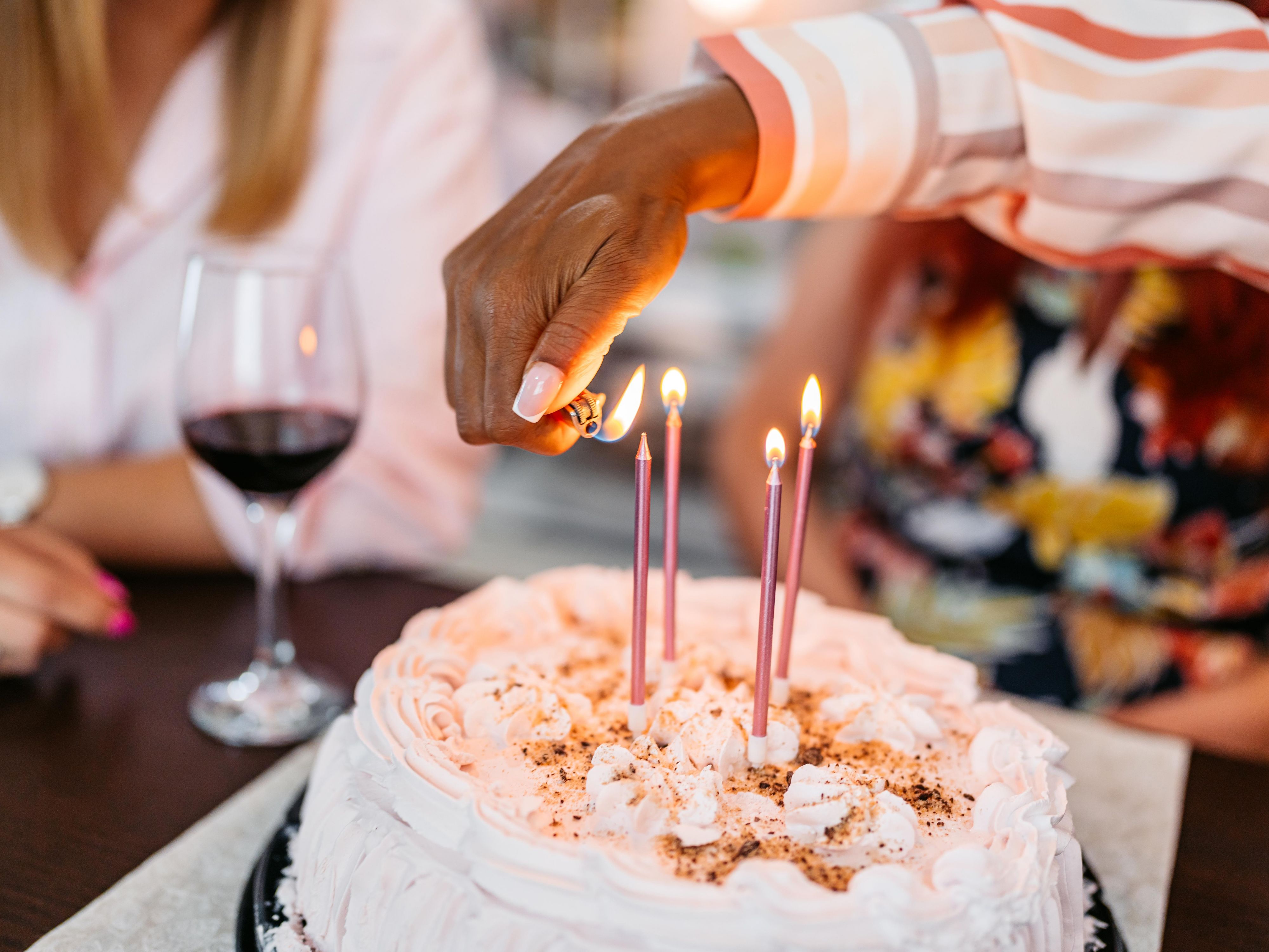Hand lighting candles on a cake