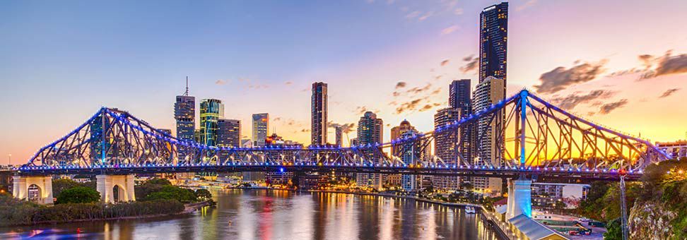 Arka planda Brisbane silüeti ile alacakaranlıkta hikaye köprüsünün görünümü